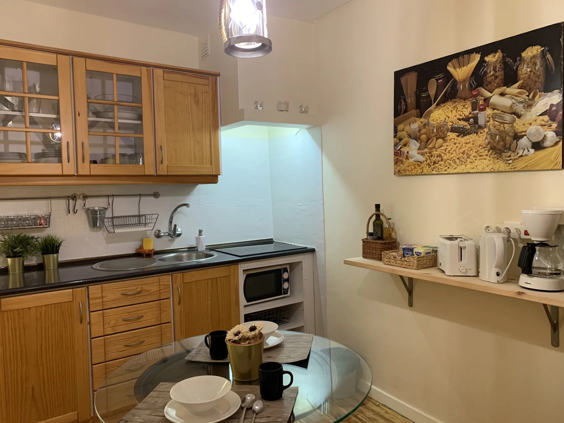 A kitchen with wooden cabinets, a sink, and a glass dining table.