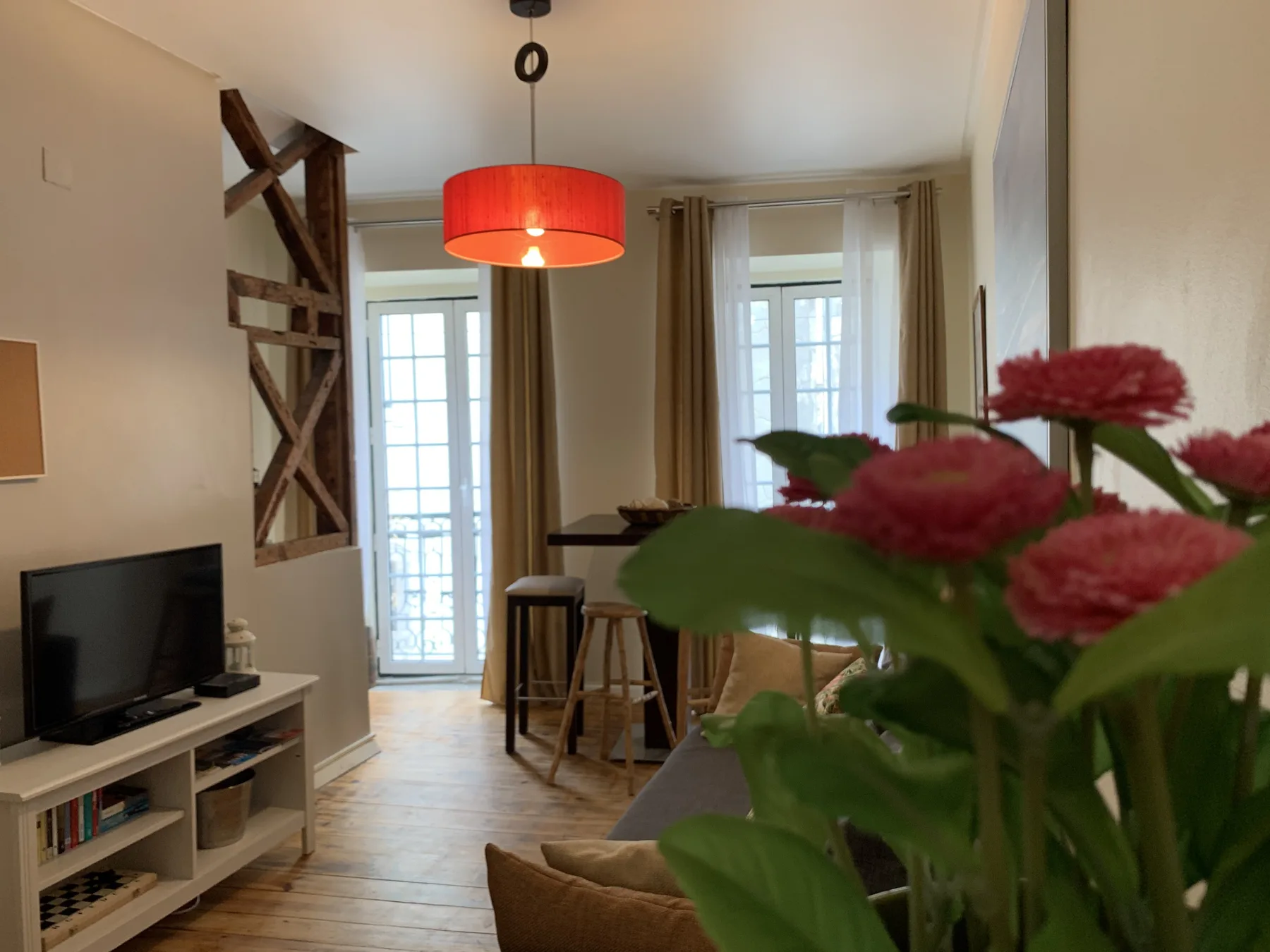 A living and dining area with a red pendant light and flowers in the foreground.