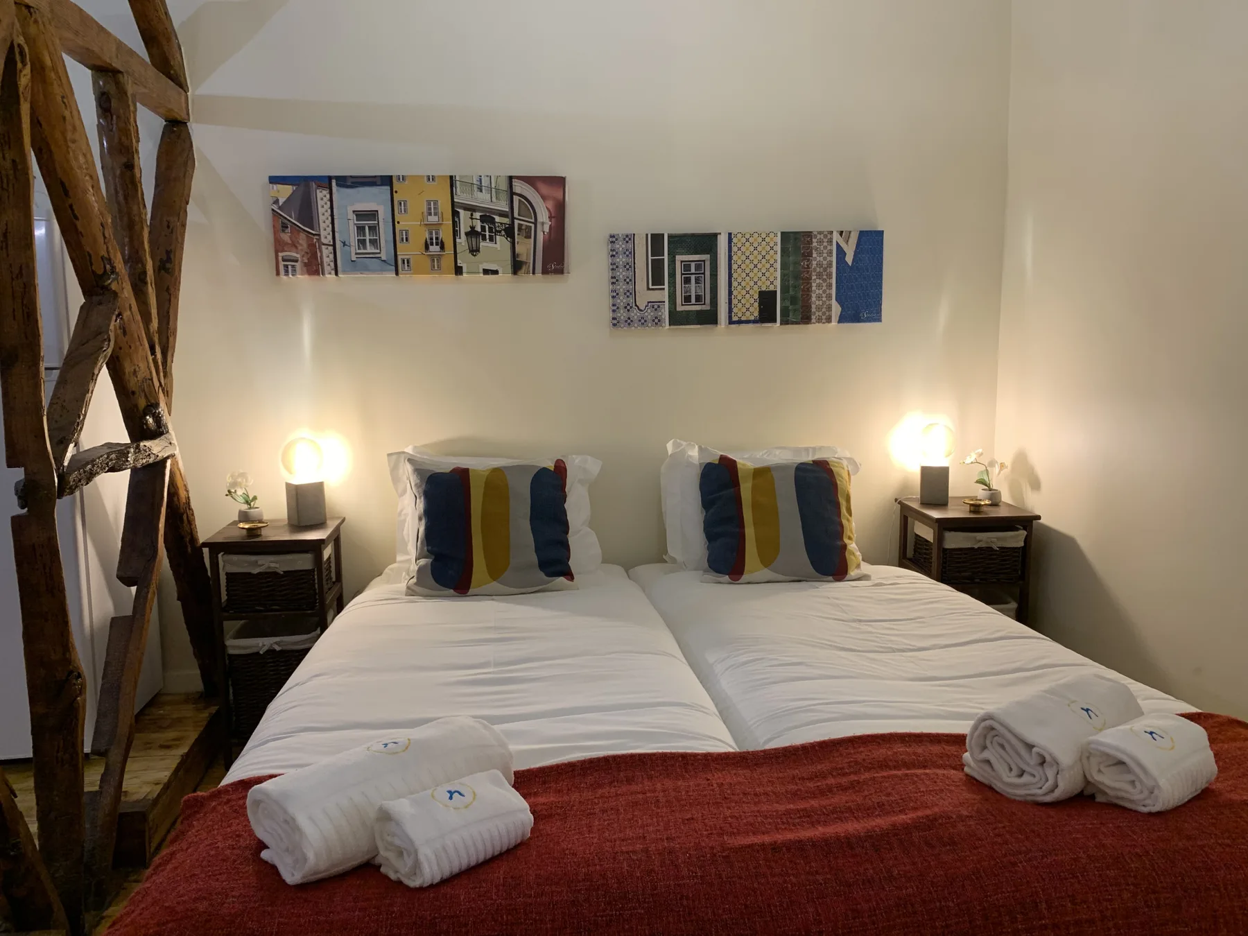 A bedroom with two beds, bedside tables, and framed artwork on the wall.