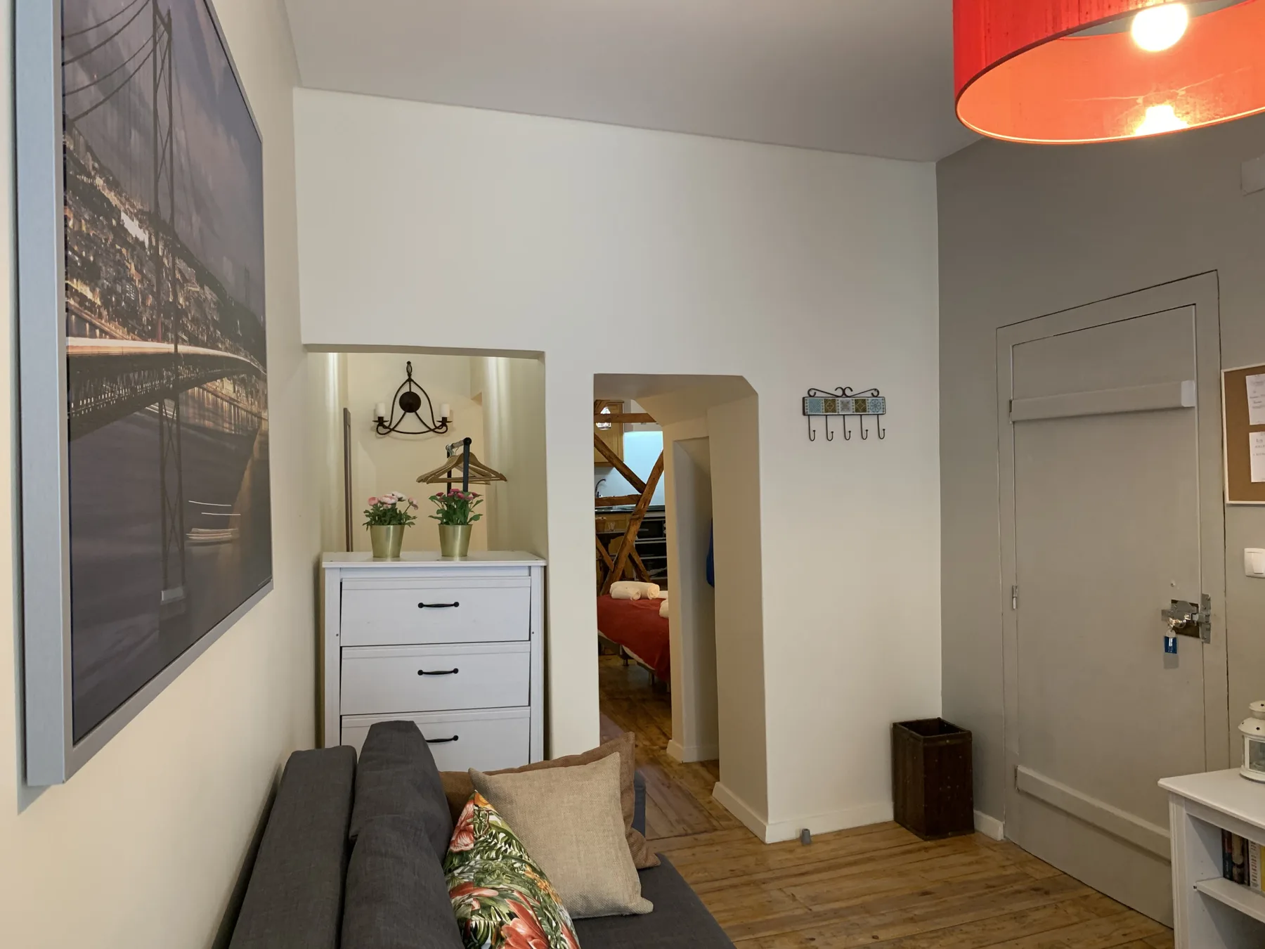 A living area with seating, a dresser, and a doorway leading to a bedroom.