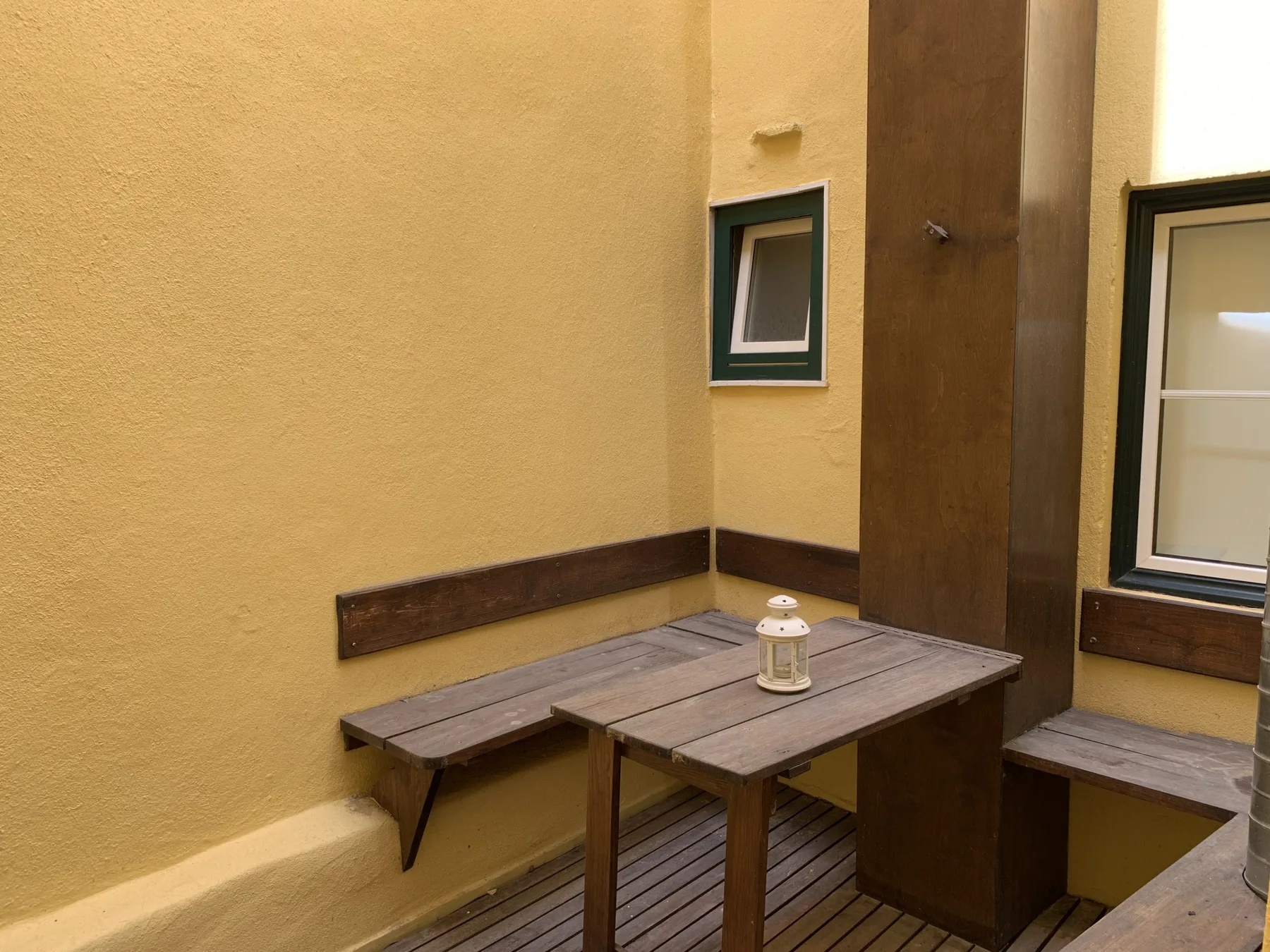 A small patio with wooden benches and a table.