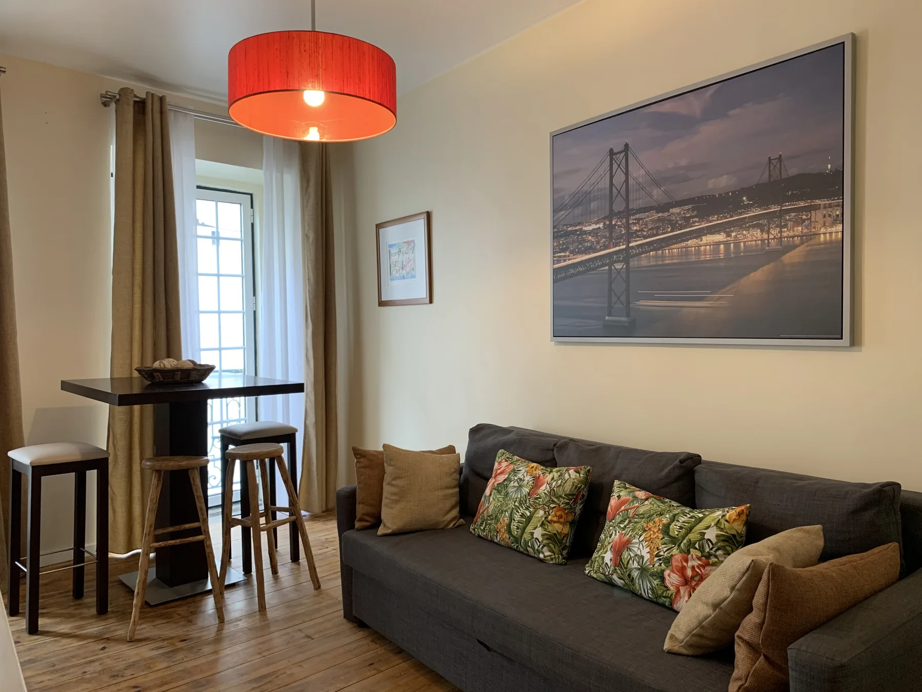 A living room with a dark sofa, a high table, and a large framed picture.