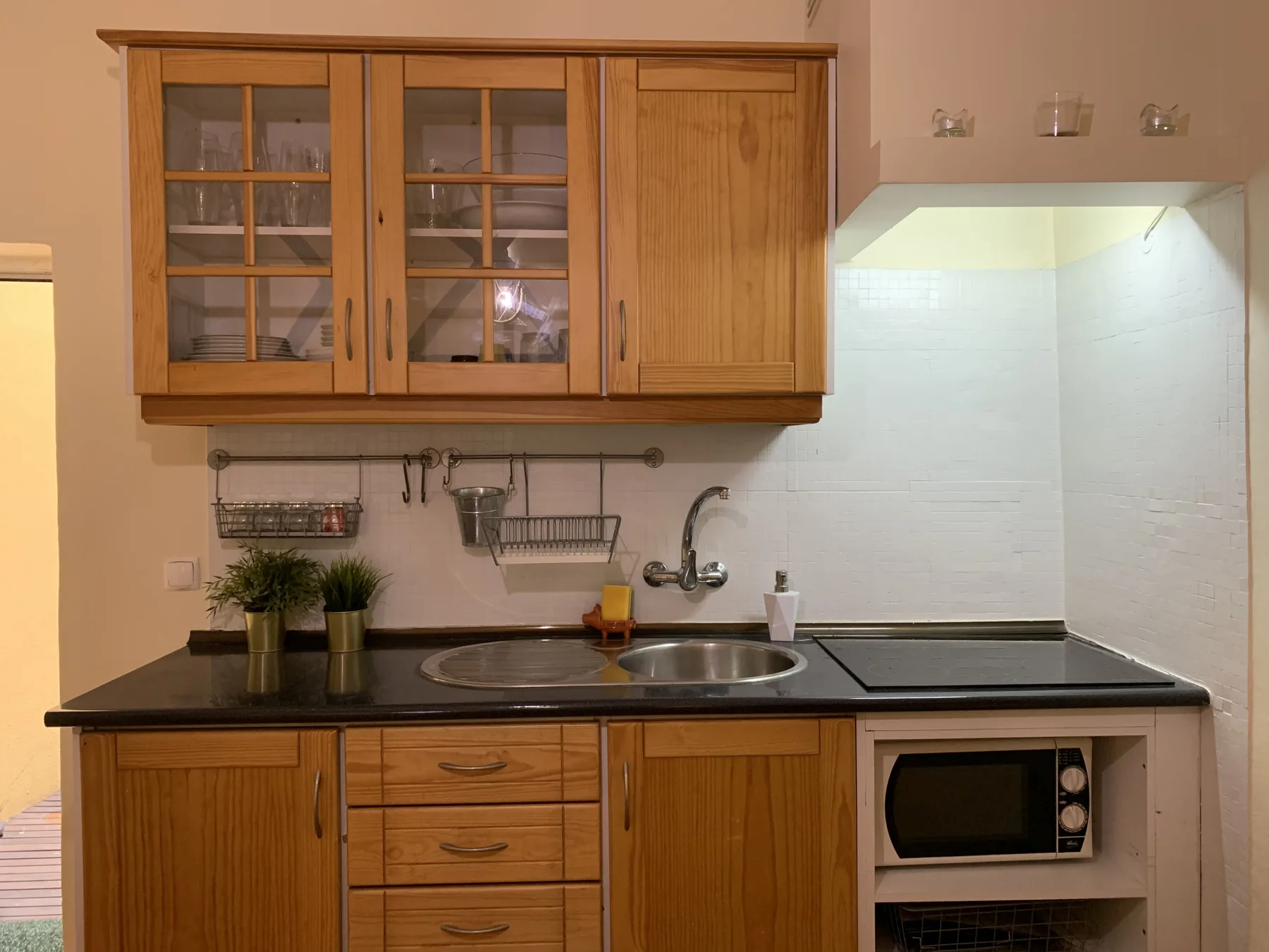 A compact kitchen with wooden cabinets, a sink, and a cooktop.