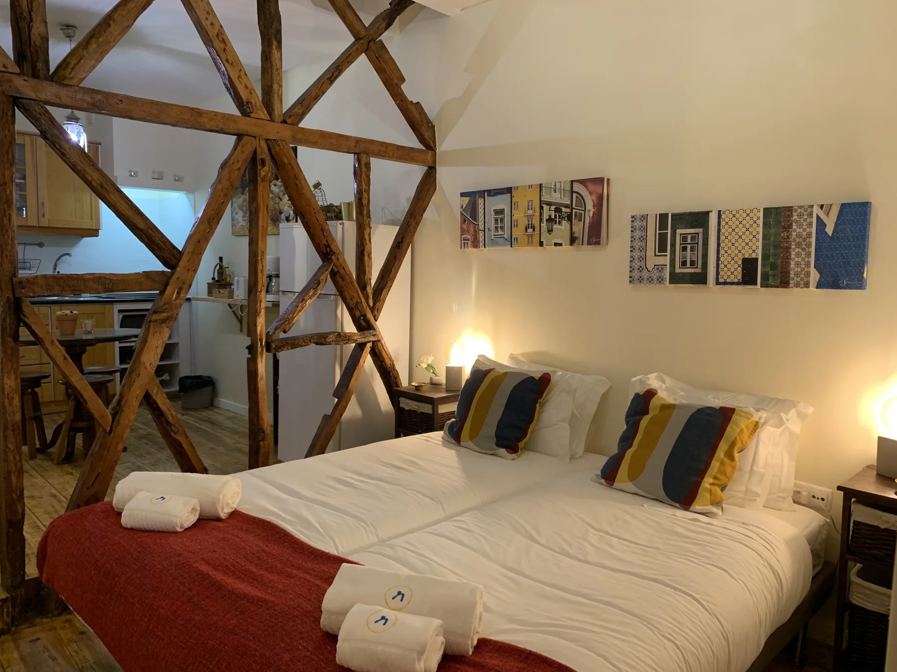 A bedroom with two beds, colorful pillows, and exposed wooden beams.