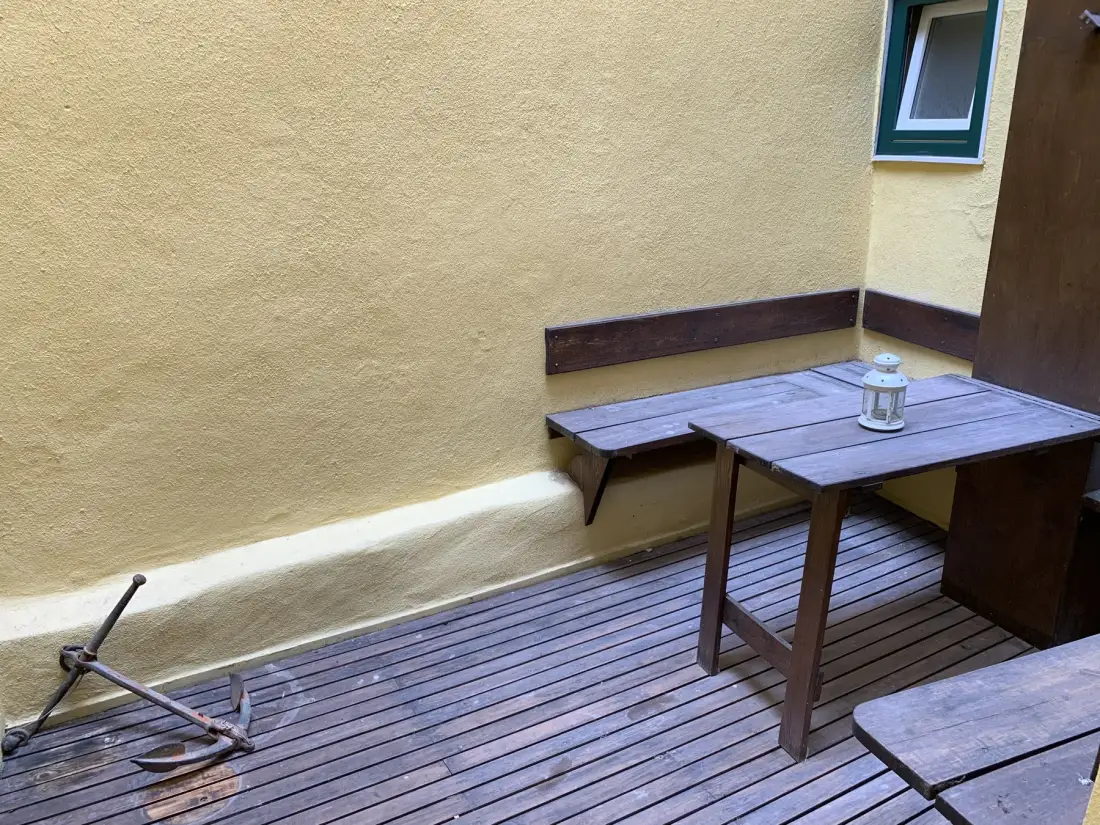 A small courtyard with wooden decking, tables, and a lantern.