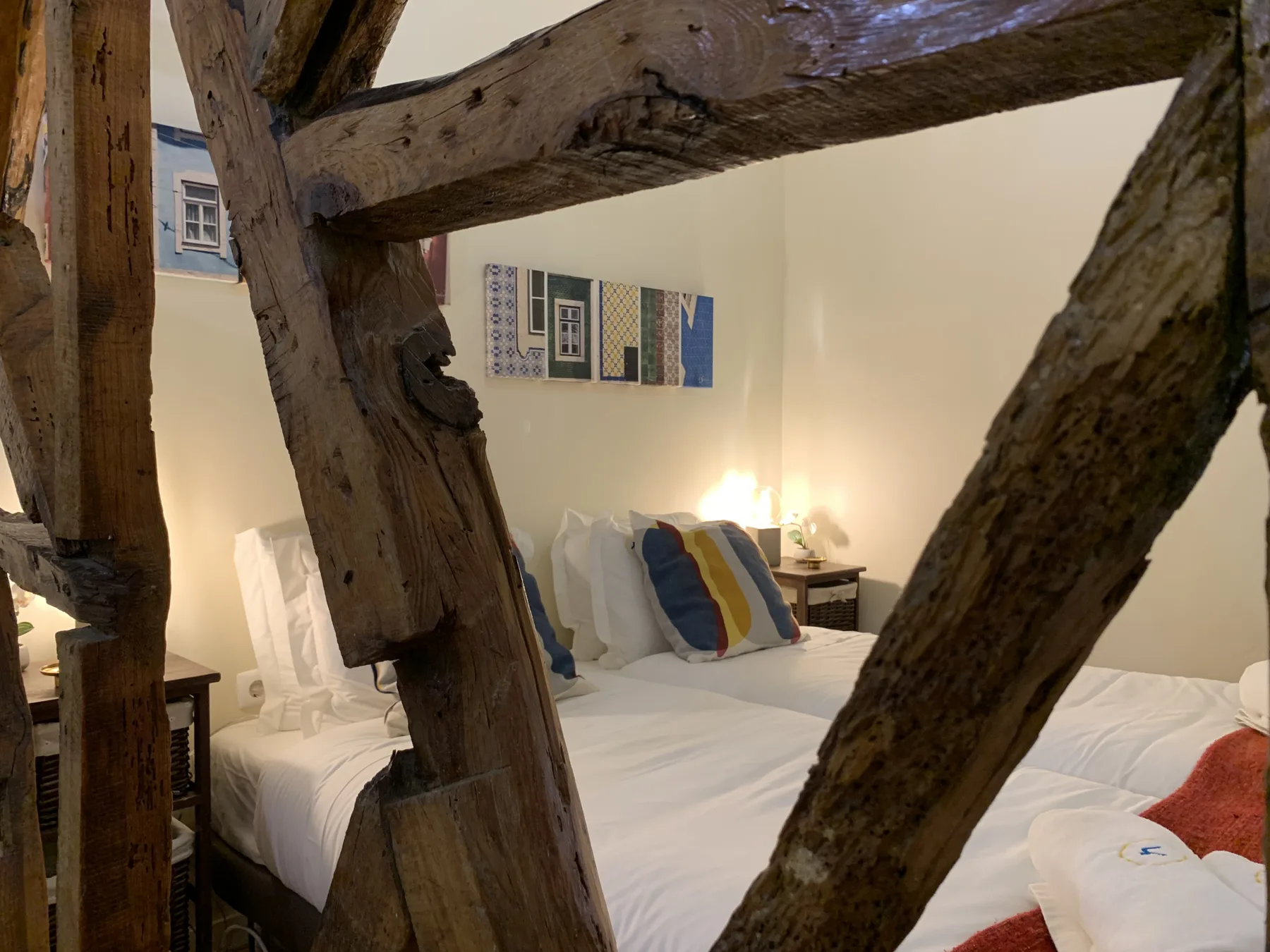 A bedroom with white bedding and exposed wooden beams.