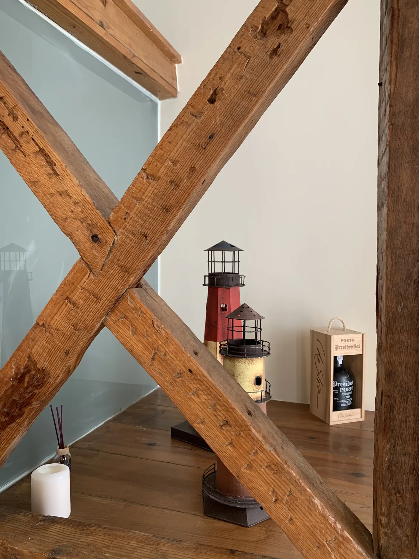 A room corner with wooden beams, a lighthouse model, and small tabletop decor.