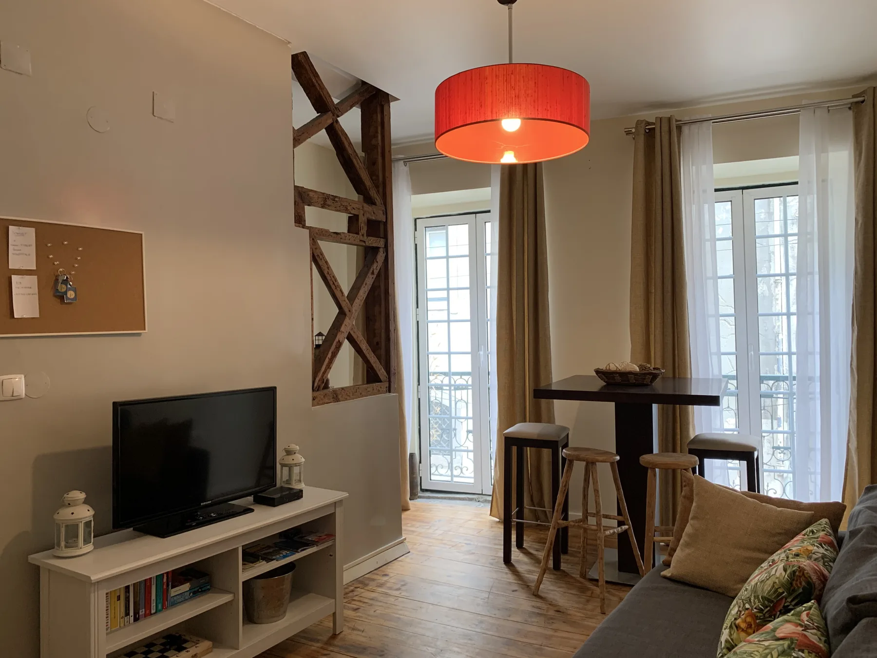 A living area with a television, bar seating, and tall windows.