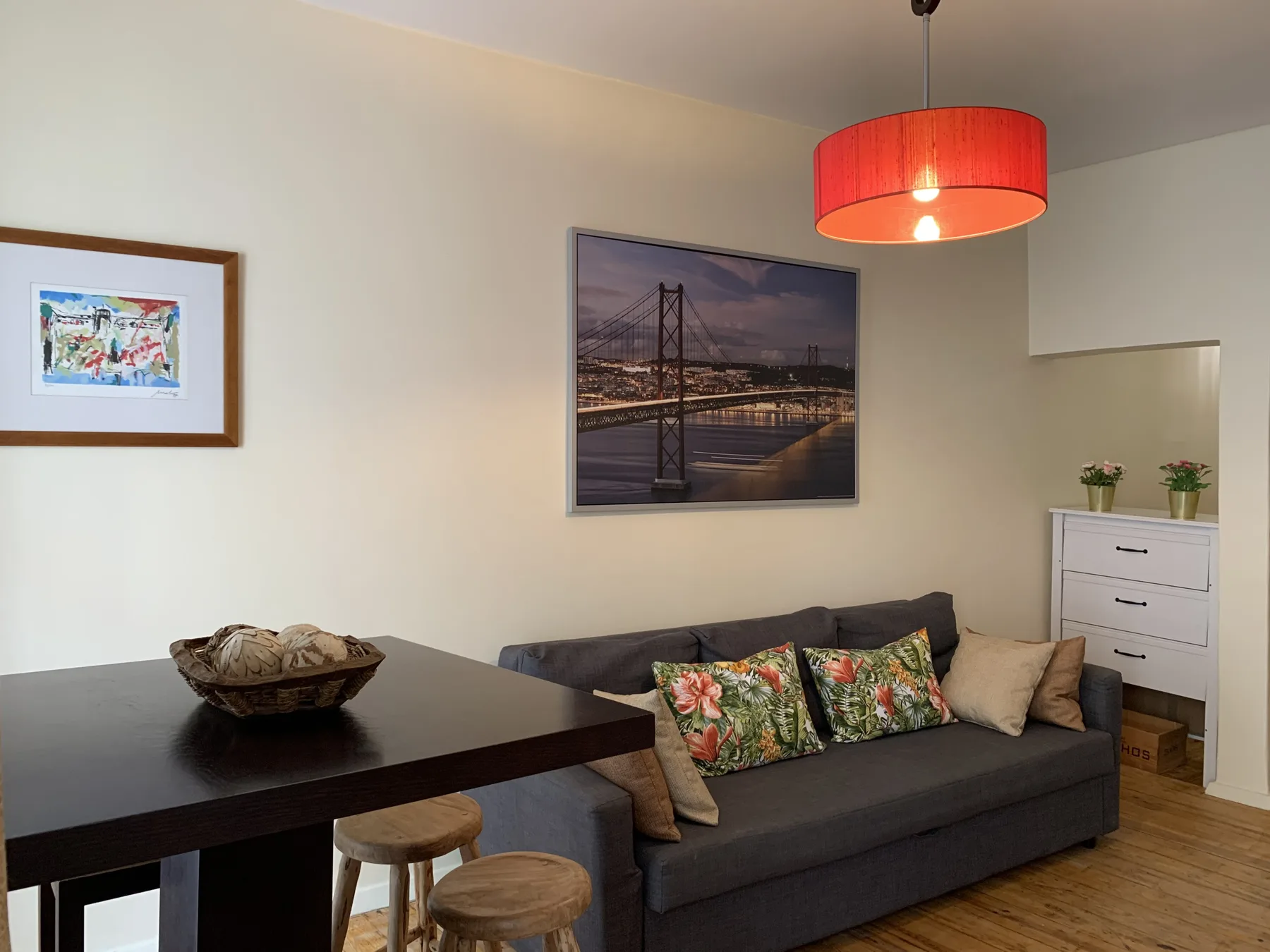Living room with a dark sofa, colorful cushions, and a dining table.
