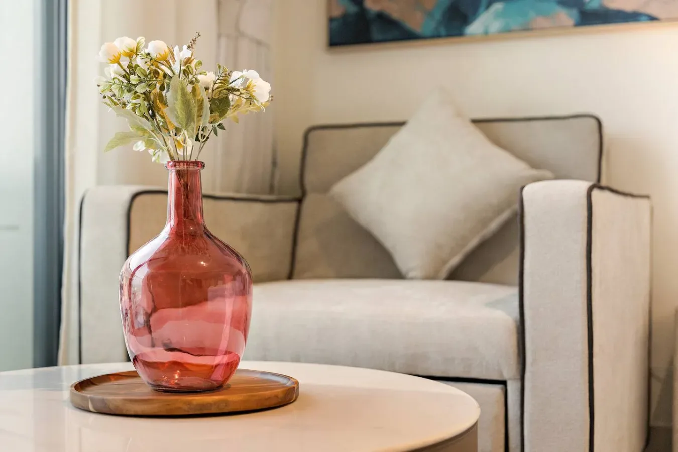 Una sala luminosa presenta un sofá beige y flores sobre una mesa de centro.