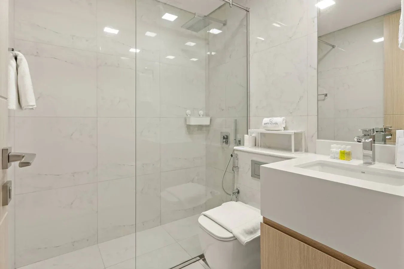 Un baño luminoso con azulejos, ducha de vidrio y lavabo con mueble.