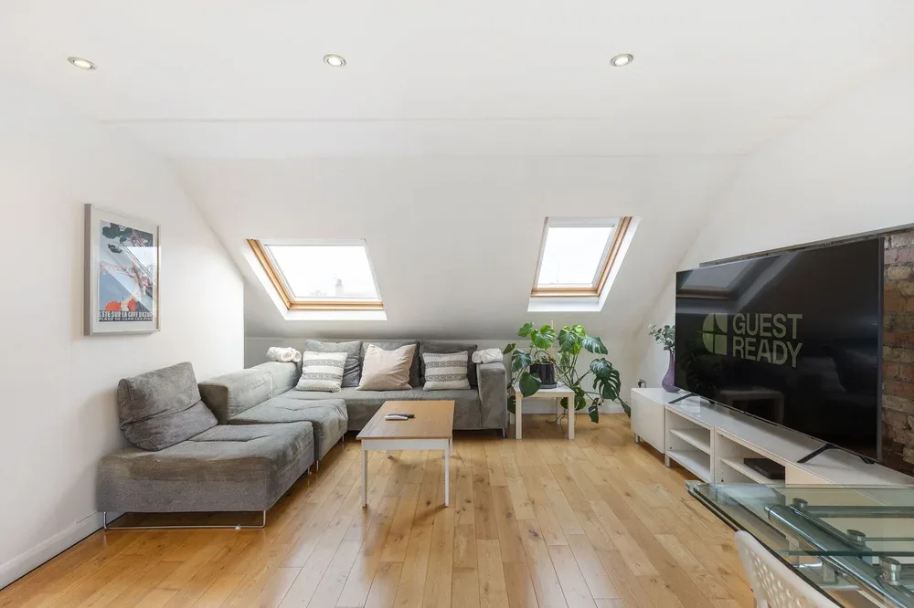 Una luminosa sala de estar con asientos, tragaluces y un televisor.