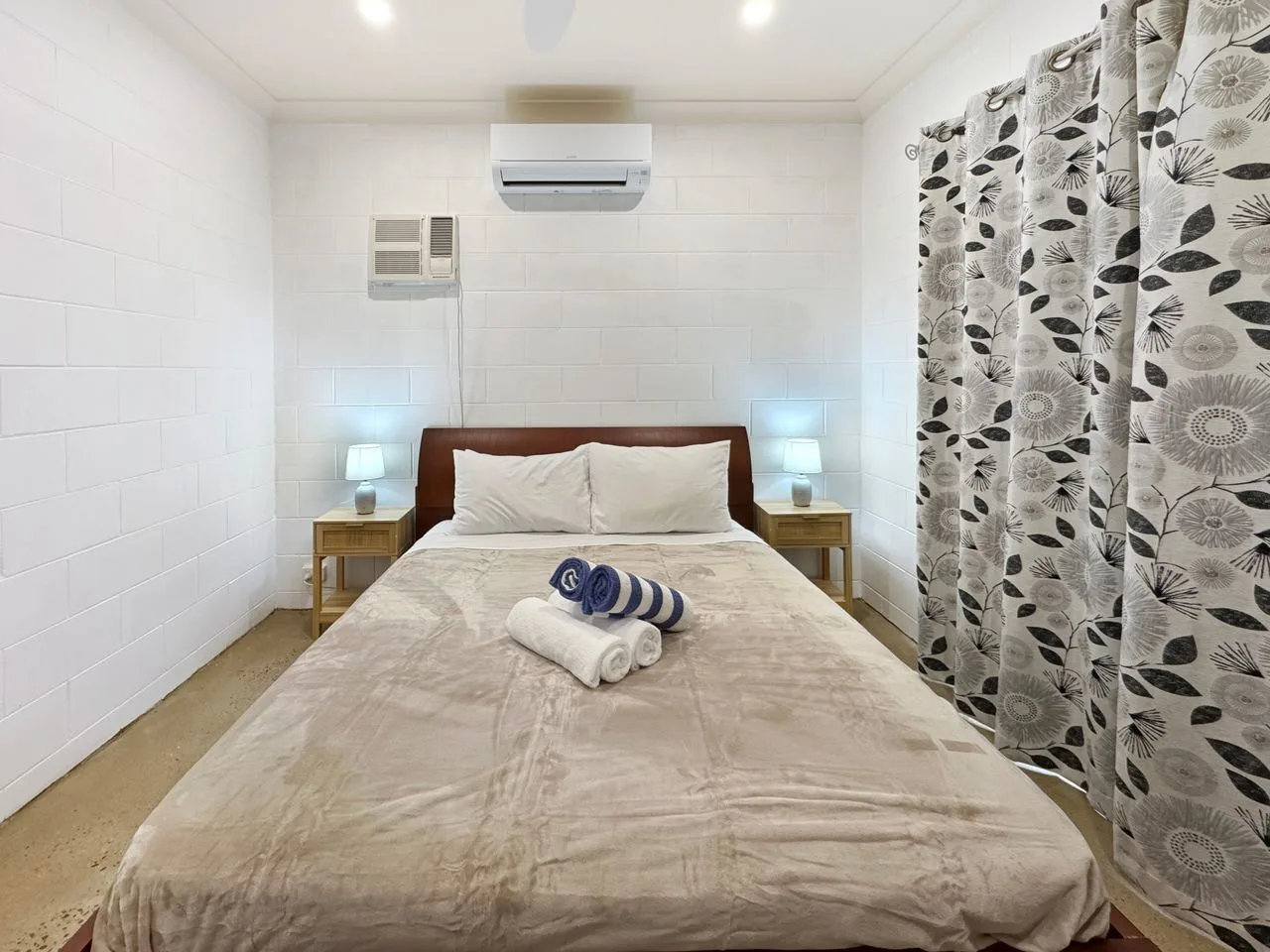 A bedroom with a double bed, bedside tables, and patterned curtains.