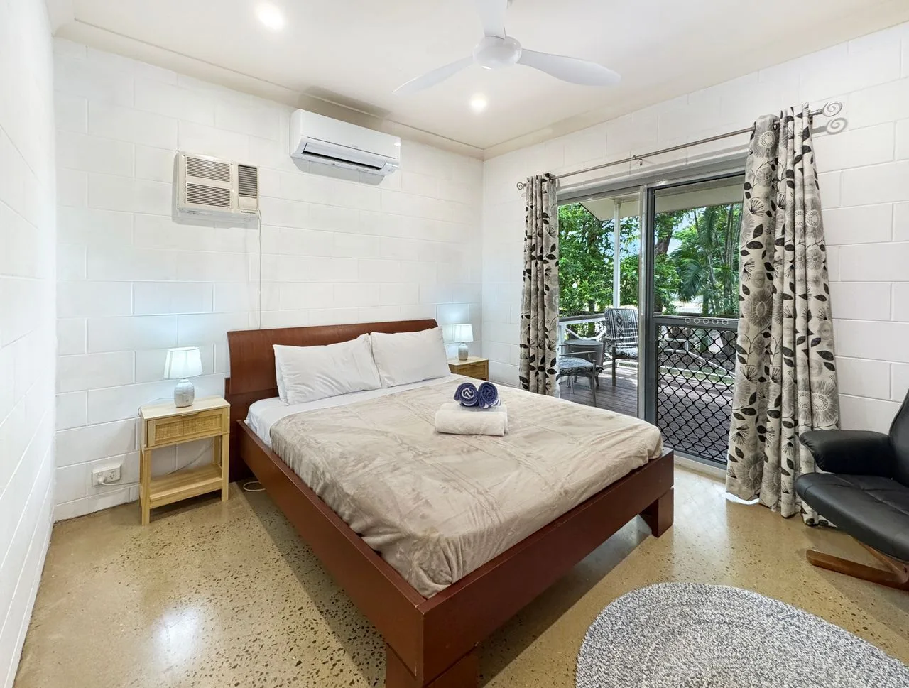 A bedroom with a bed beside glass doors opening onto a balcony.