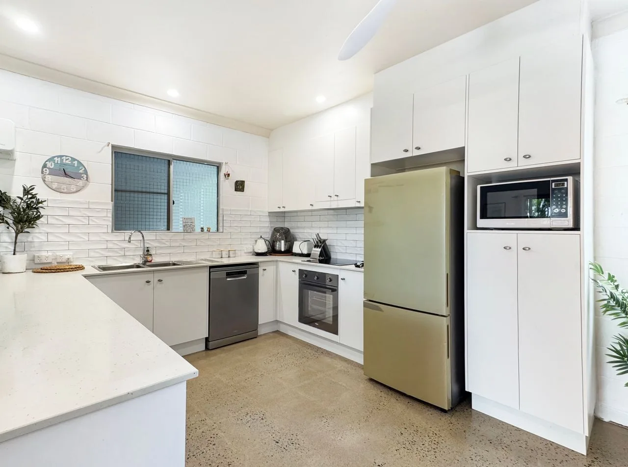 A bright kitchen with white cabinets and built-in appliances.