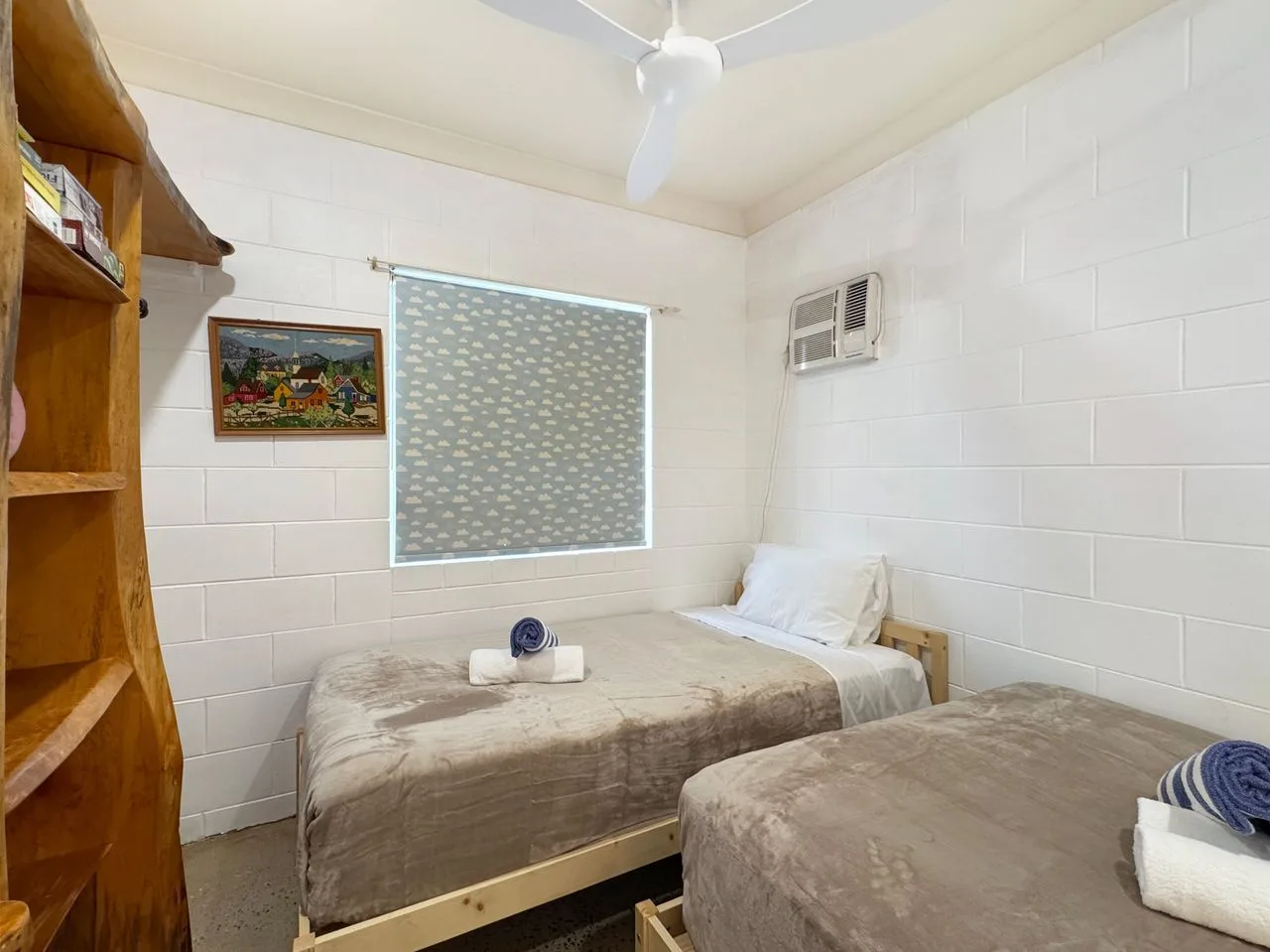A bedroom with two beds, a window, and a ceiling fan.