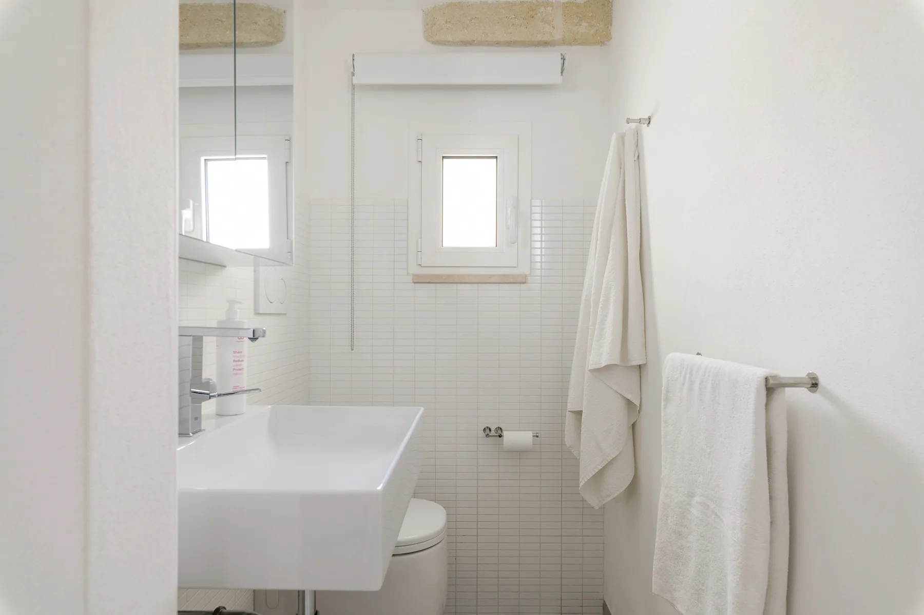 Un baño luminoso con lavabo, inodoro y toallas.