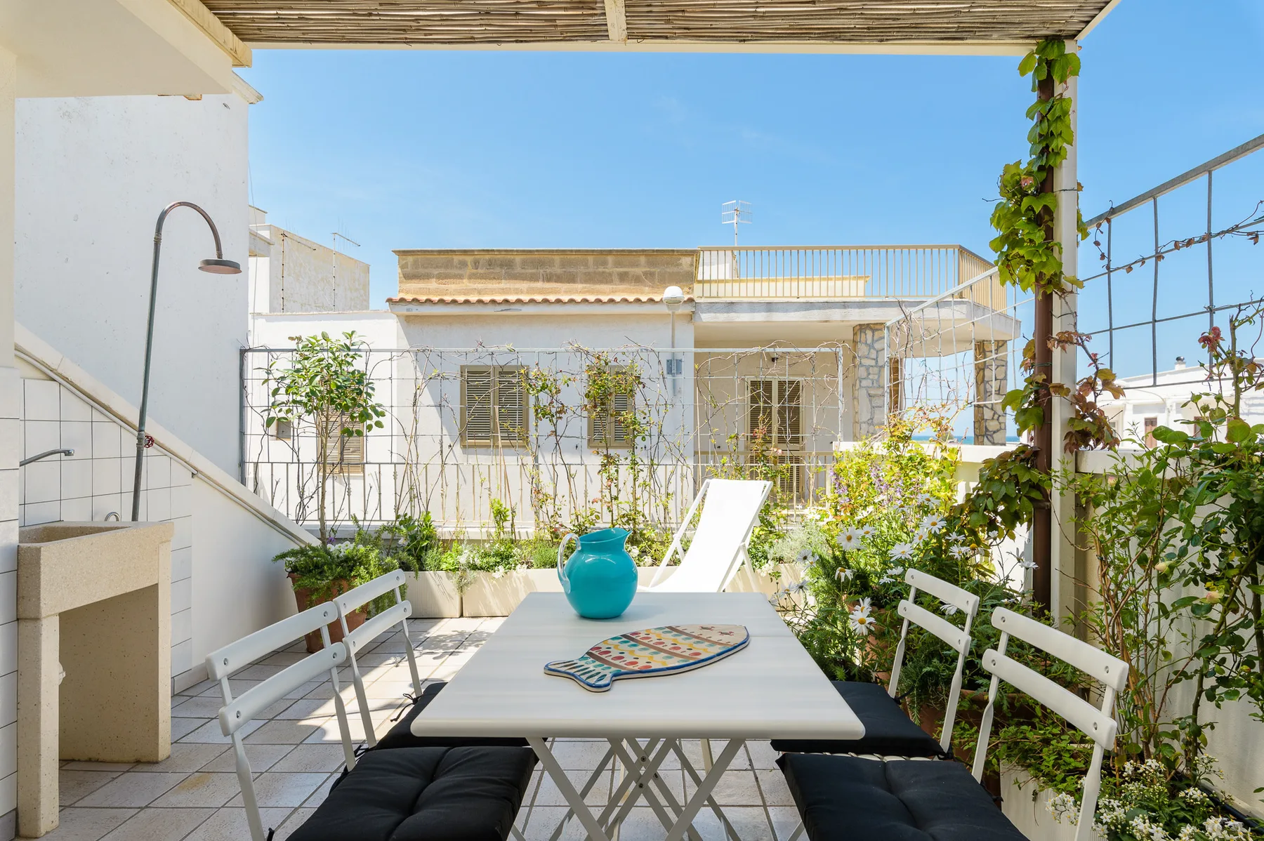 Un patio soleado al aire libre con una mesa y plantas.