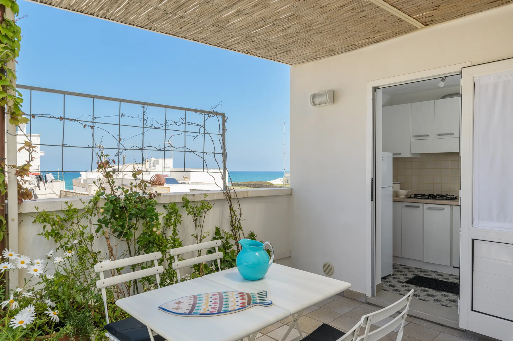 Una terraza en la azotea con una mesa blanca y vistas al mar.