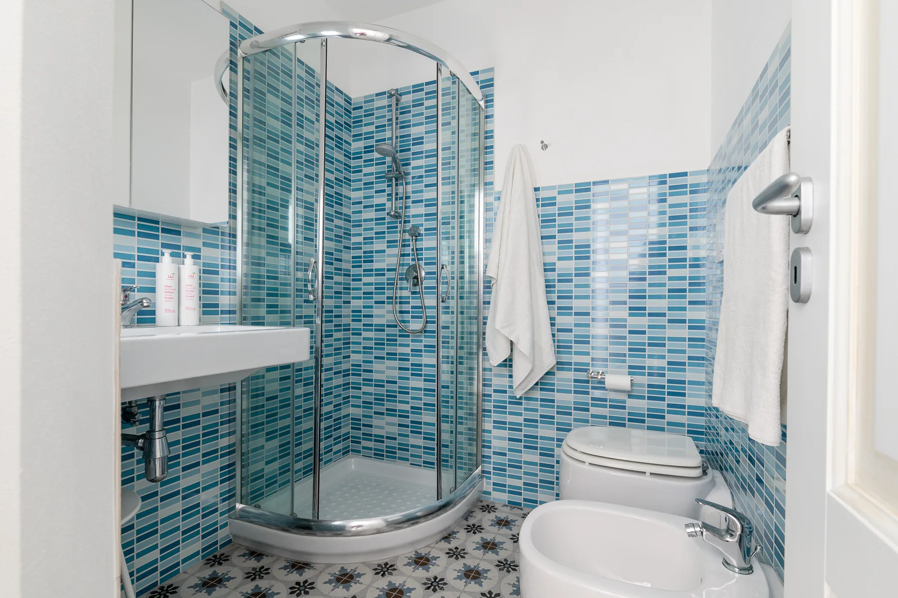 Un baño con azulejos, una ducha curva de vidrio y un bidé.