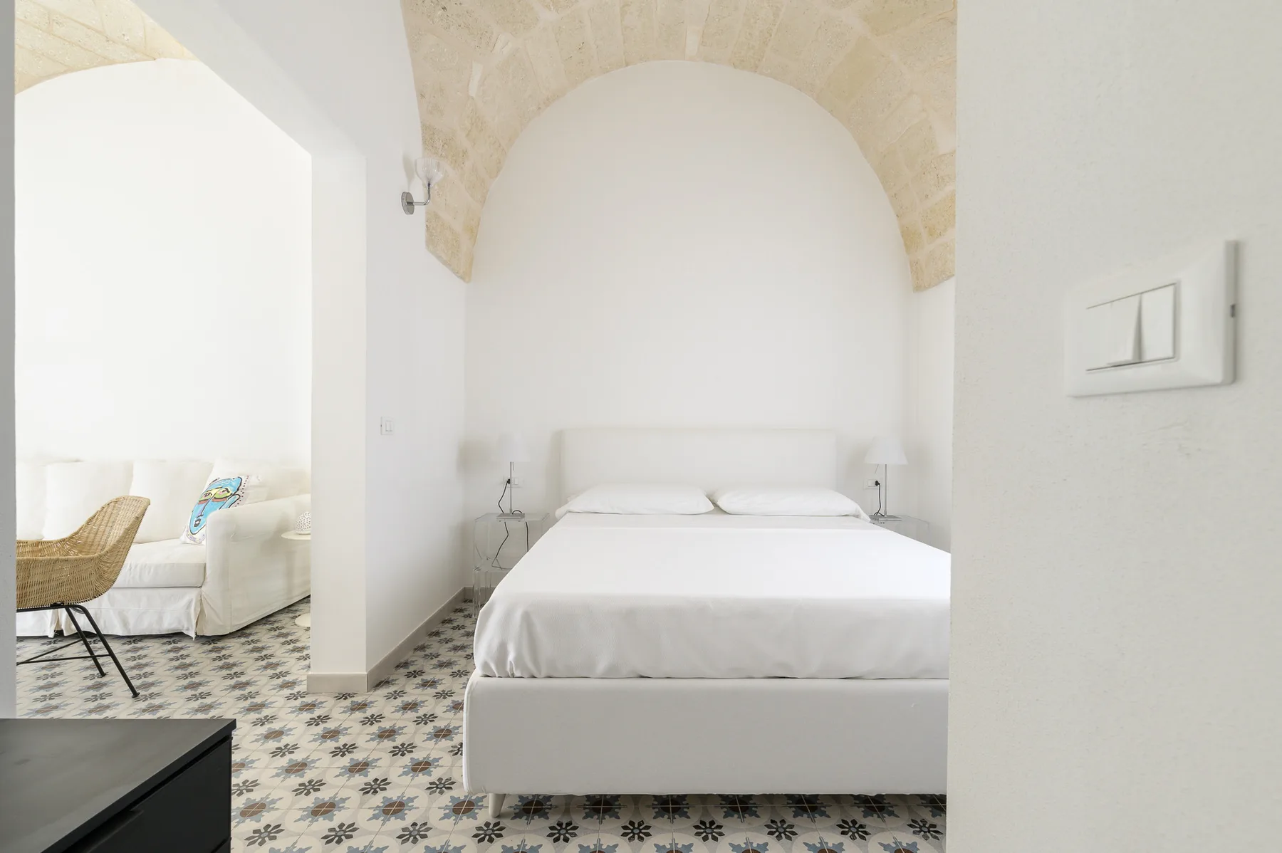 Un dormitorio luminoso con una cama blanca y un techo abovedado de piedra.