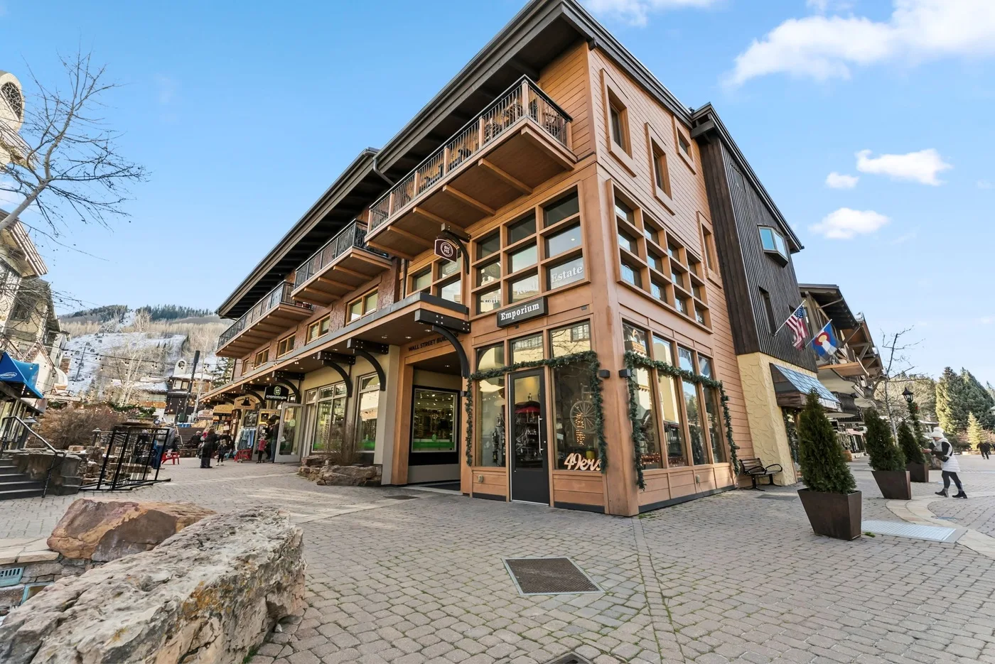 A multi-story commercial building with balconies stands along a paved pedestrian street.