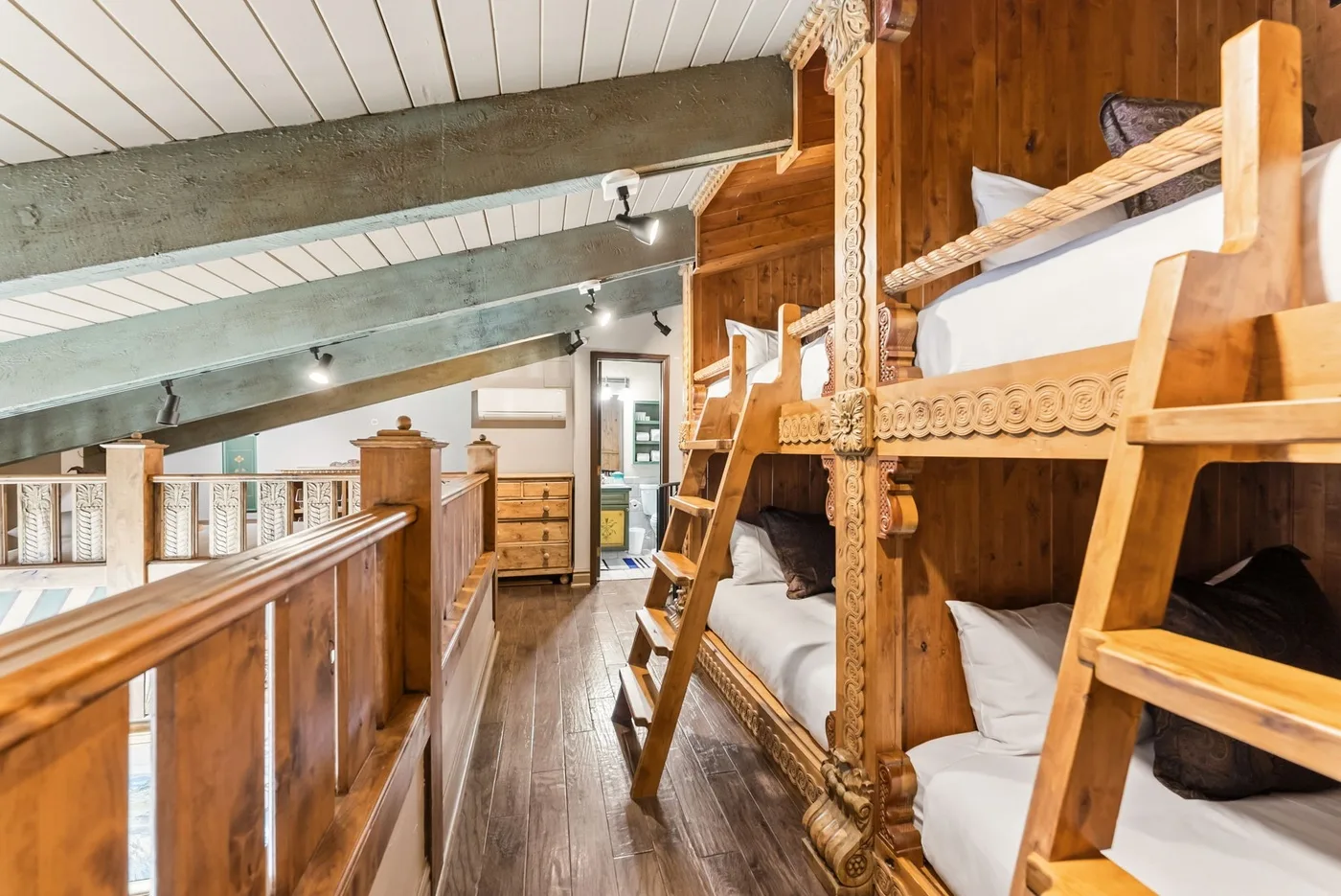 A wooden loft bedroom has built-in bunk beds beneath a sloped ceiling.