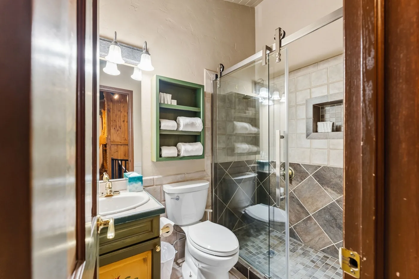 A bathroom with a sink, toilet, and glass shower.