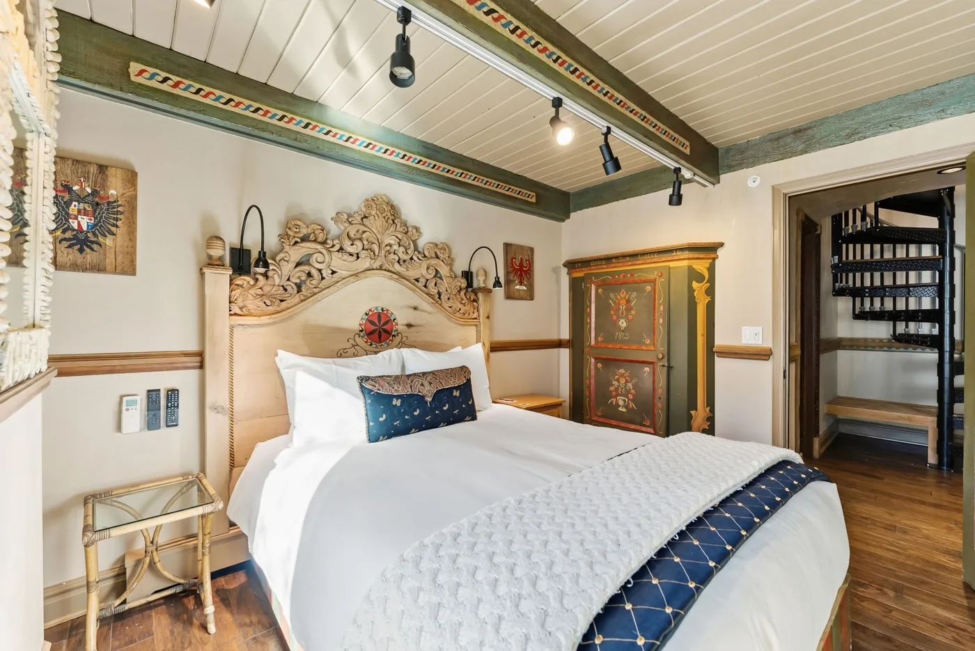 A bedroom with an ornate bed and a painted cabinet.