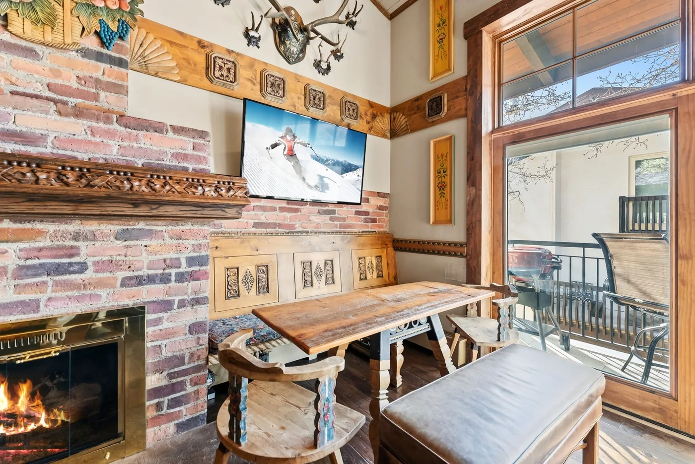 A rustic dining area with a wooden table beside a brick fireplace.