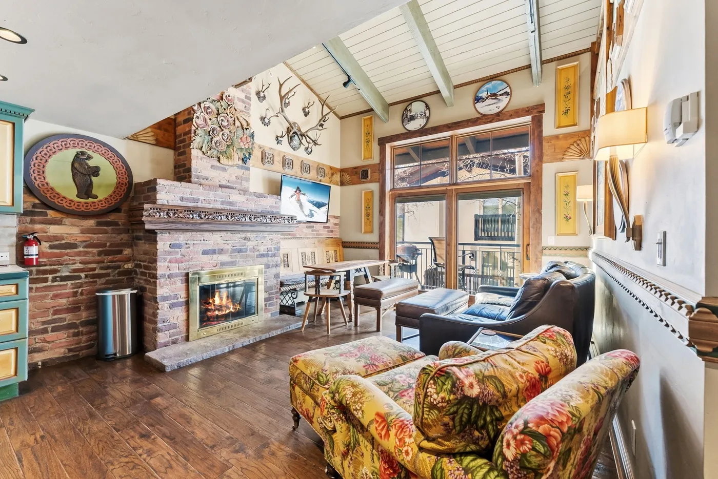 A living room with a brick fireplace, seating, and large windows.