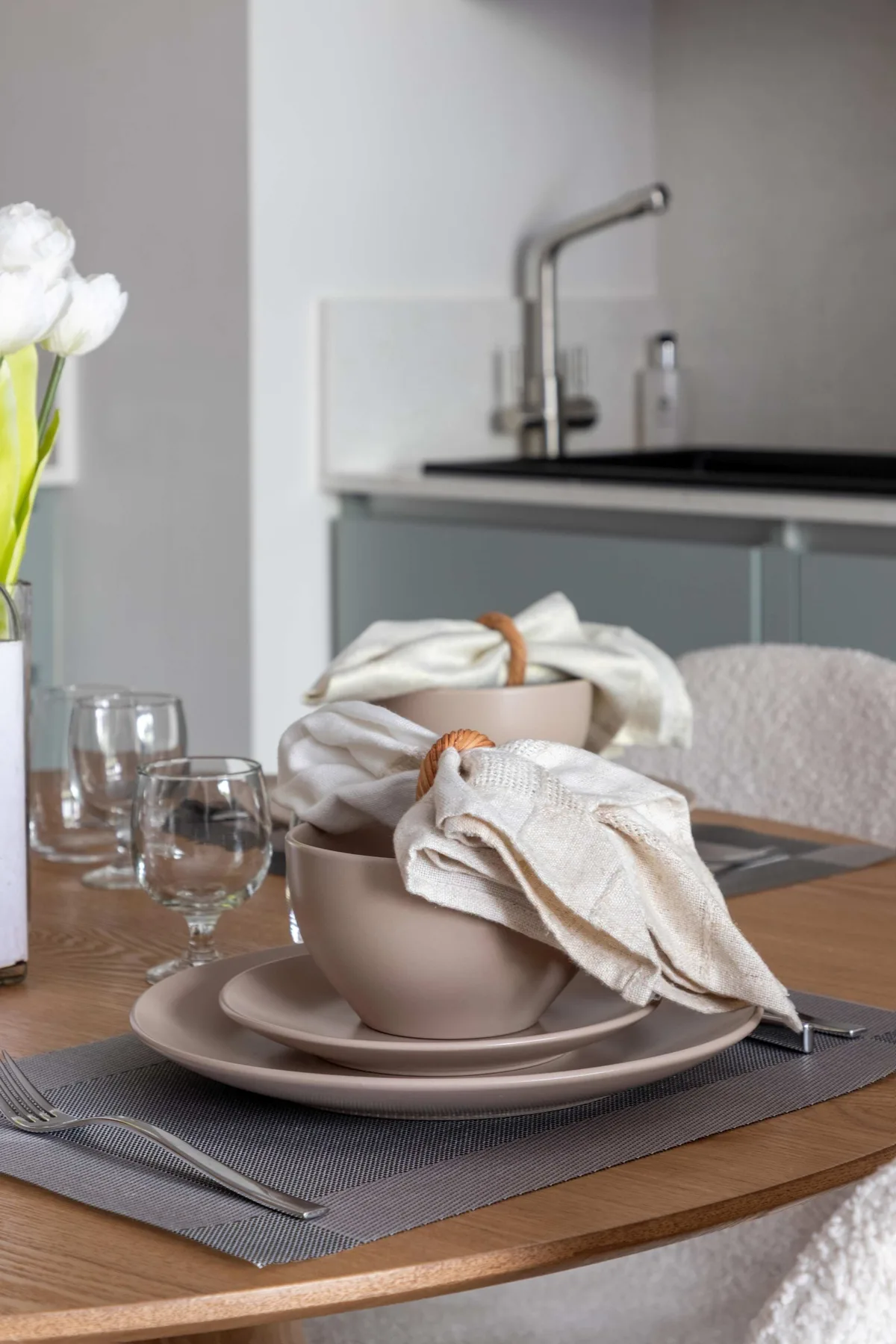 Una mesa está puesta con platos apilados, toallas dobladas y vasos.