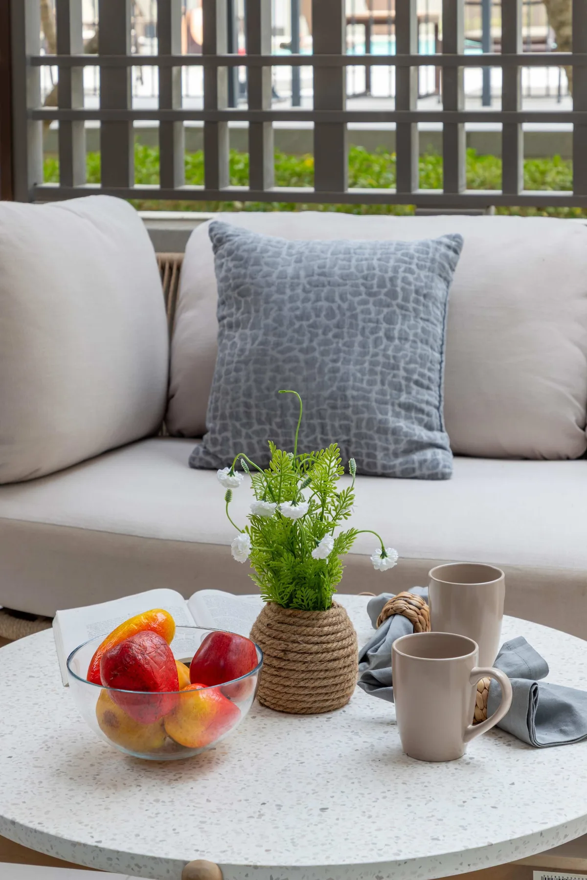 Una zona de estar con un sofá claro y una mesa redonda con tazas y flores.