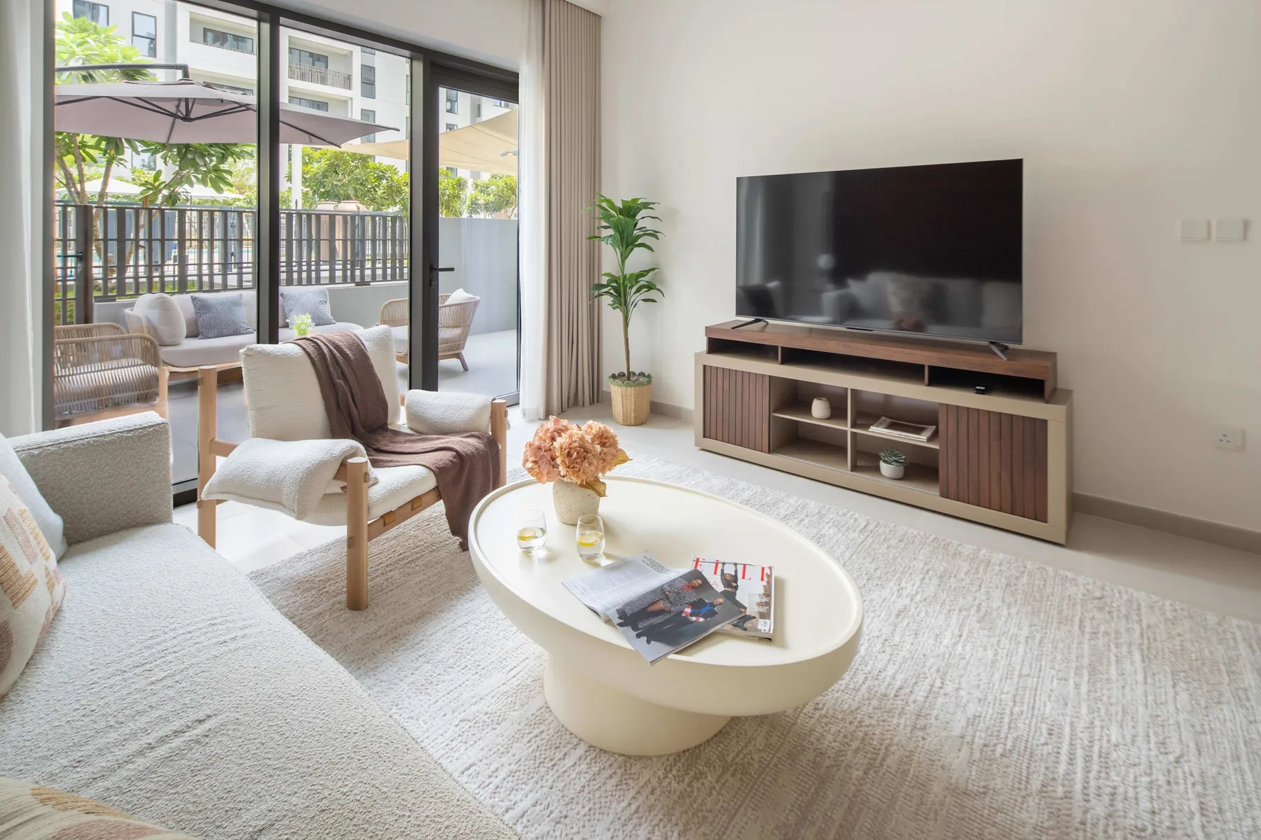Una sala luminosa con televisor y asientos junto a grandes ventanales.