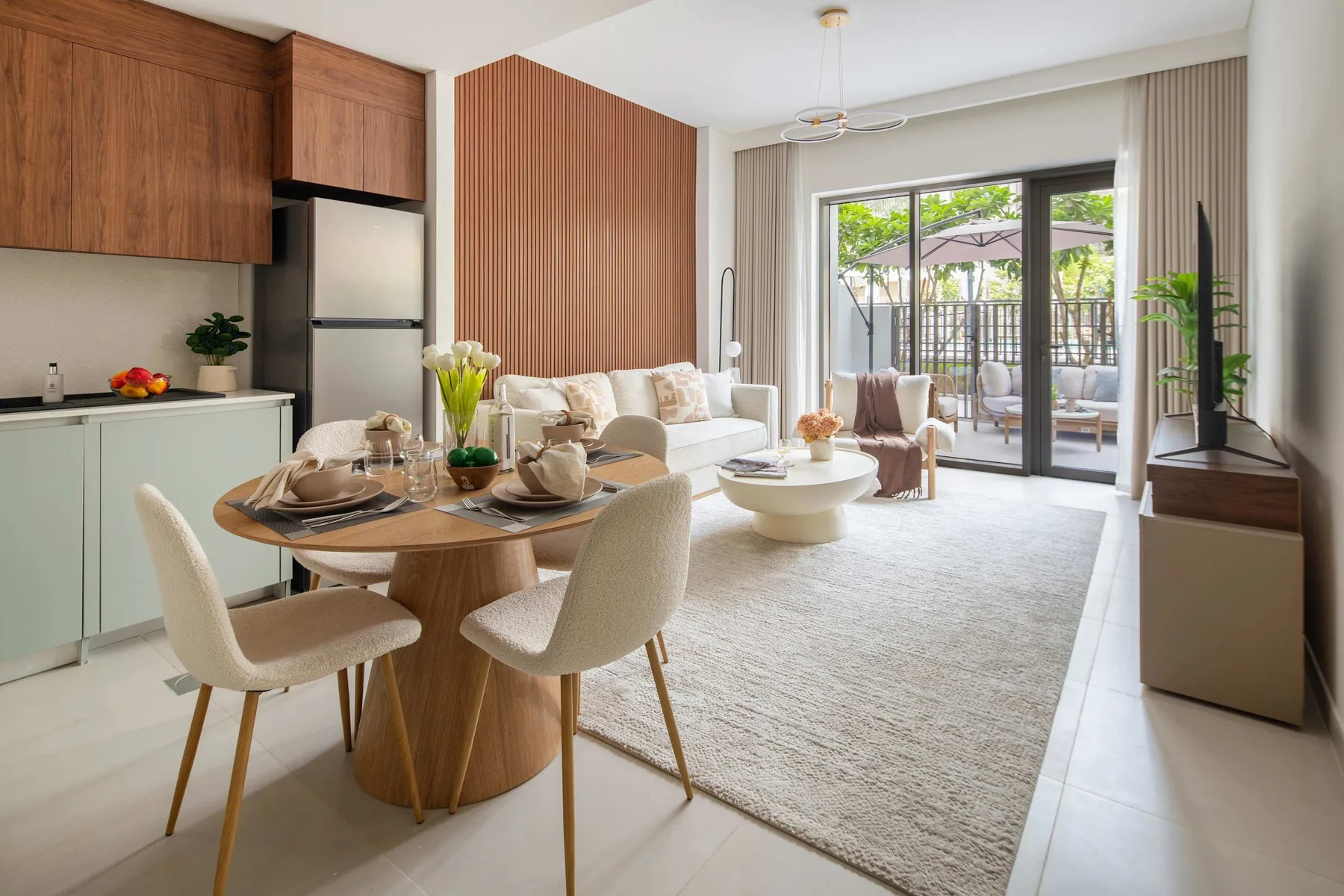 Un comedor y sala de estar de planta abierta, con una mesa redonda y grandes puertas de cristal.