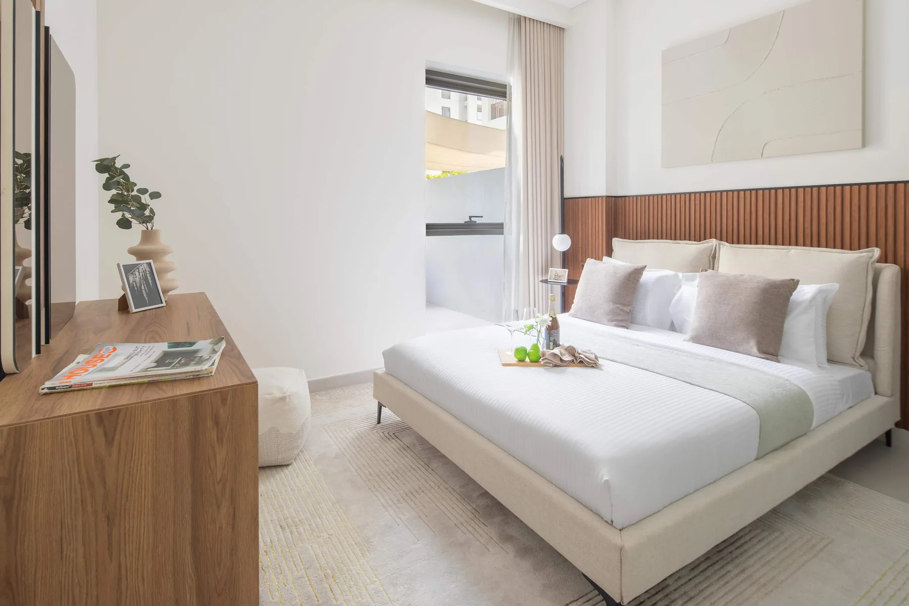 Un dormitorio luminoso con una cama bien tendida y una cómoda de madera.