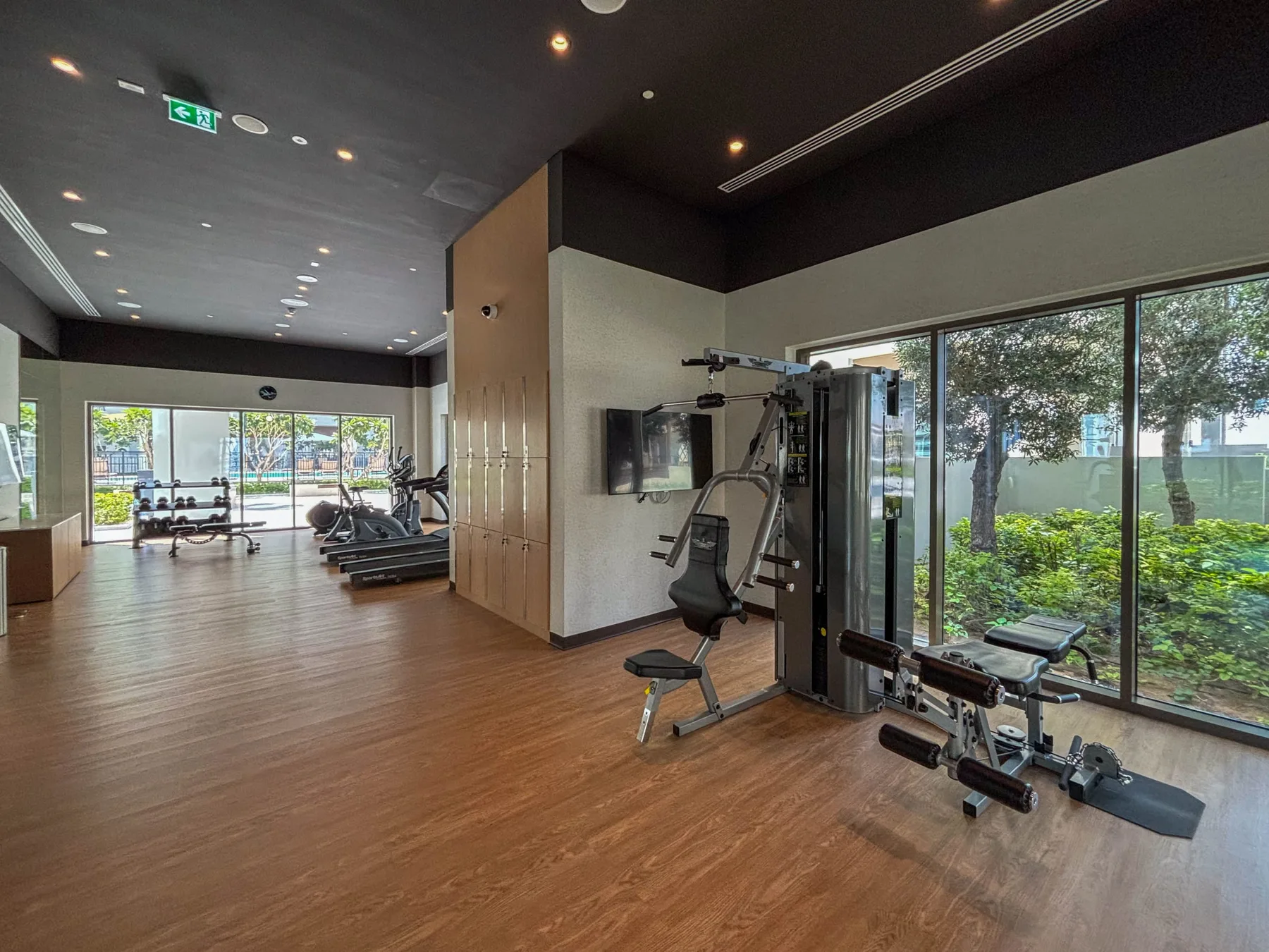 Una sala de ejercicios luminosa con equipos junto a grandes ventanales.
