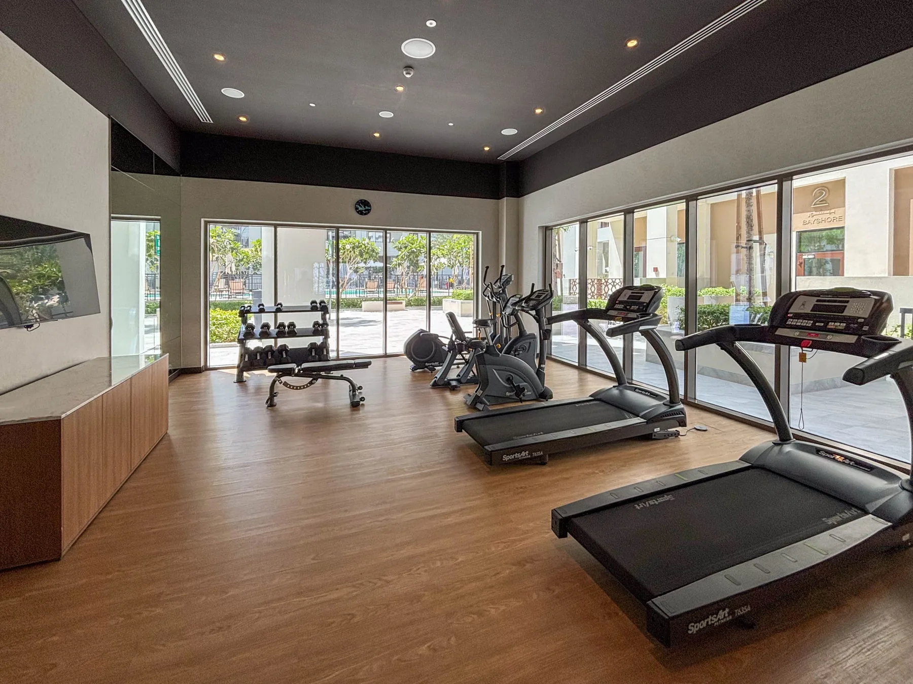 Una sala de fitness con cintas de correr, bicicletas estáticas y pesas.