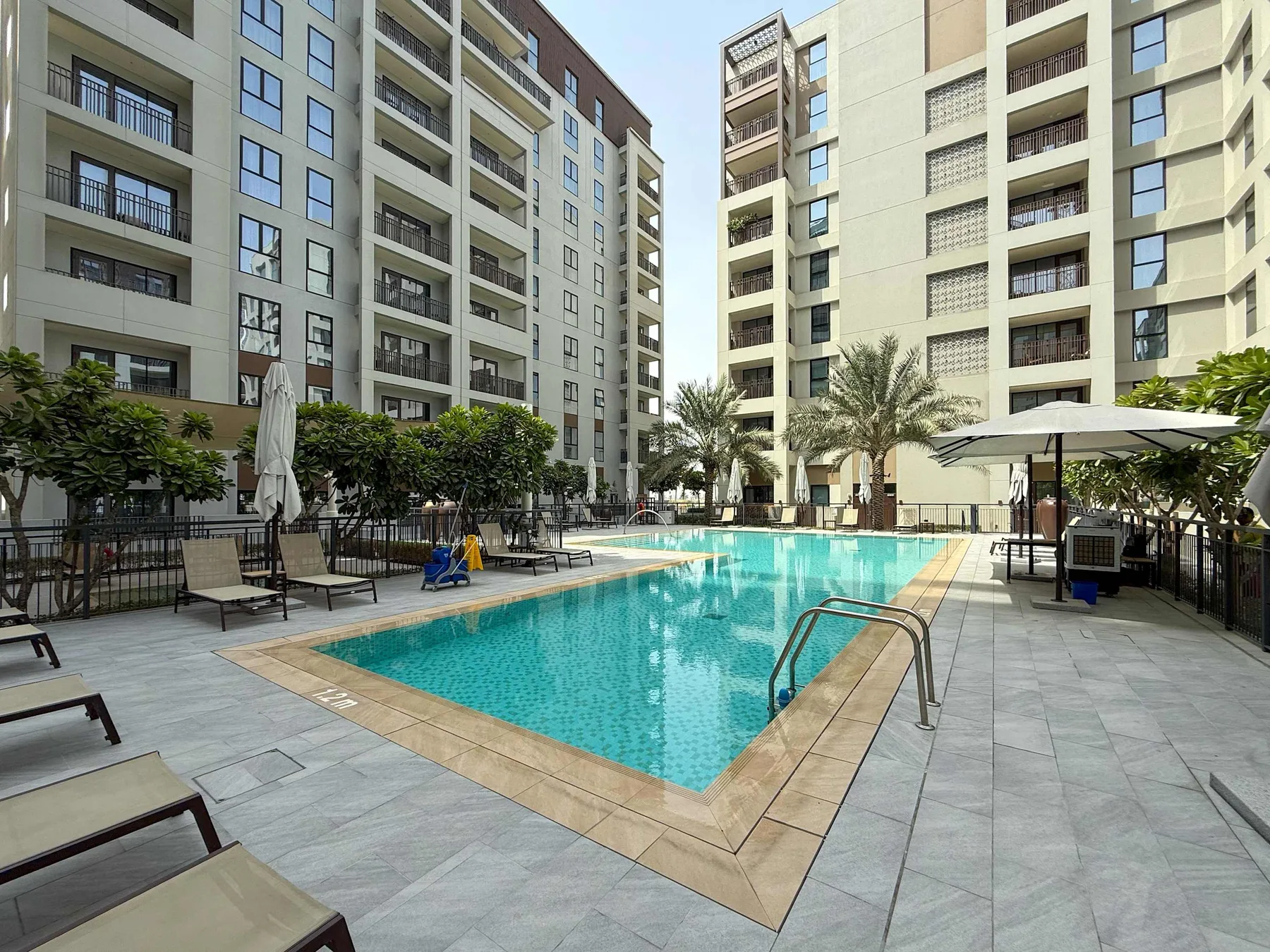 Una piscina al aire libre está rodeada de edificios altos y asientos de patio.