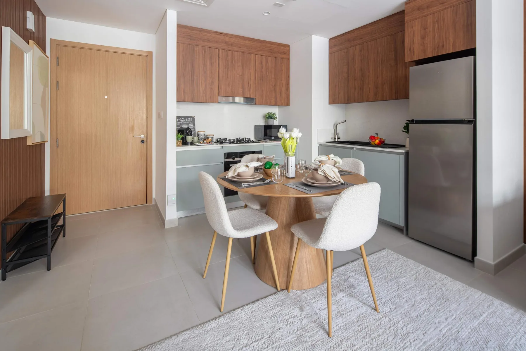 Un comedor con la mesa puesta está junto a una cocina compacta.
