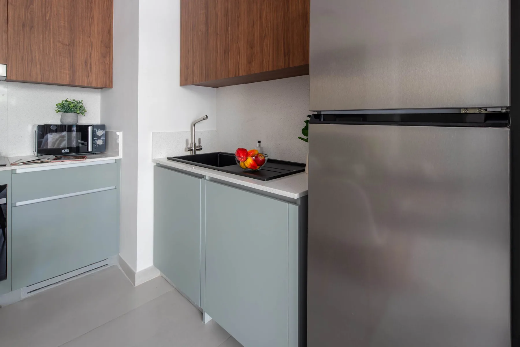 Una cocina moderna con gabinetes claros, una encimera y un refrigerador de acero inoxidable.