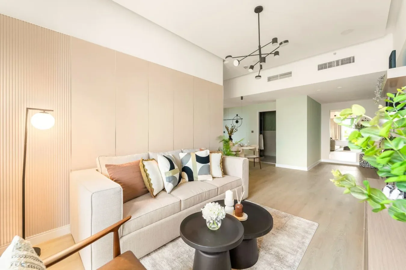 A bright living room with seating, a rug, and a pair of round coffee tables.