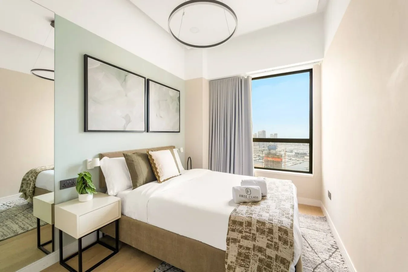 A bright bedroom with a neatly made bed beside a large window.
