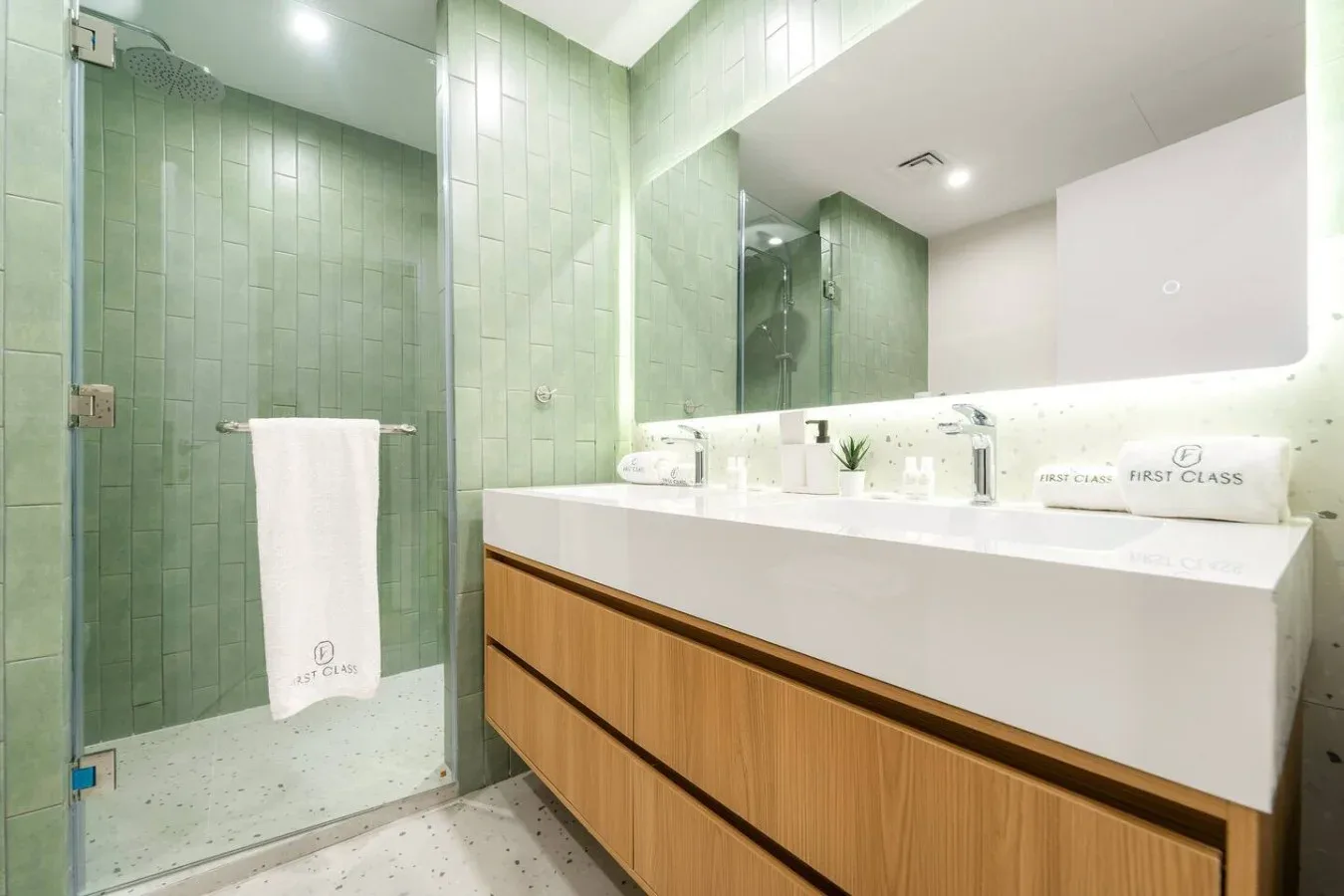 A modern bathroom with a glass shower and a long vanity beneath a mirror.