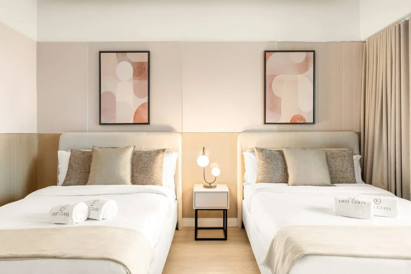 A bright bedroom with two beds and a small table between them.