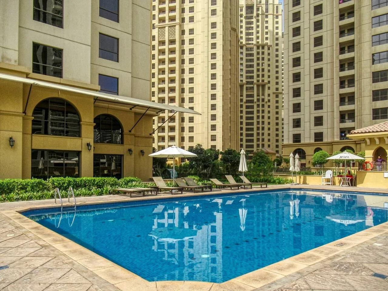 A swimming pool sits in a courtyard surrounded by tall residential buildings.