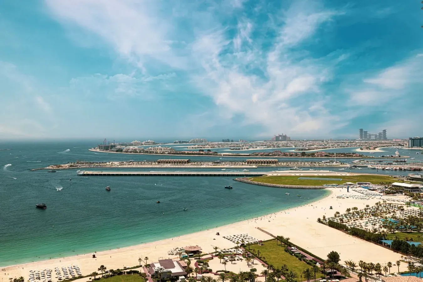 Vista aérea de una playa de arena curva y mar turquesa junto a una ciudad costera.