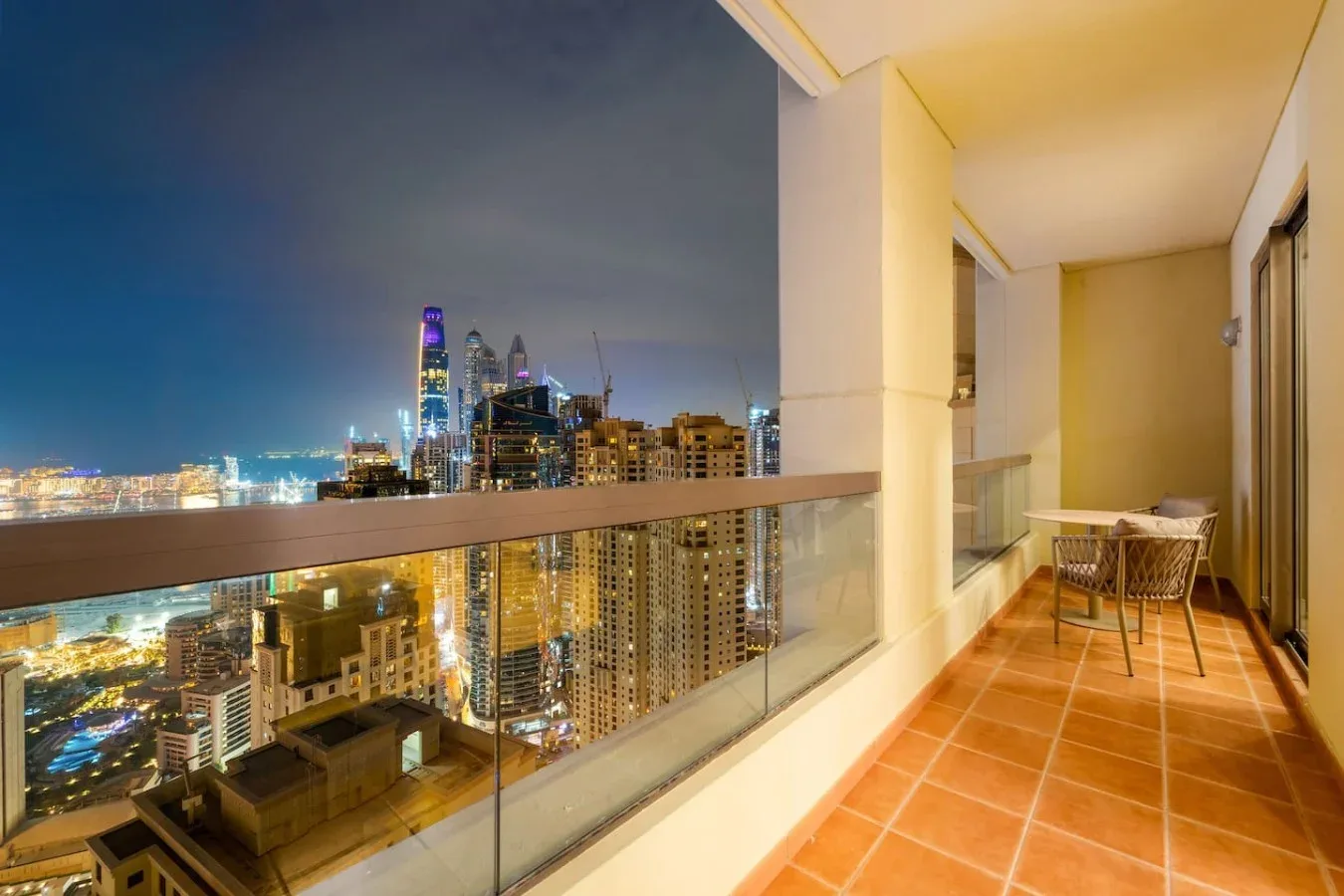 A balcony overlooks a brightly lit city skyline at night.