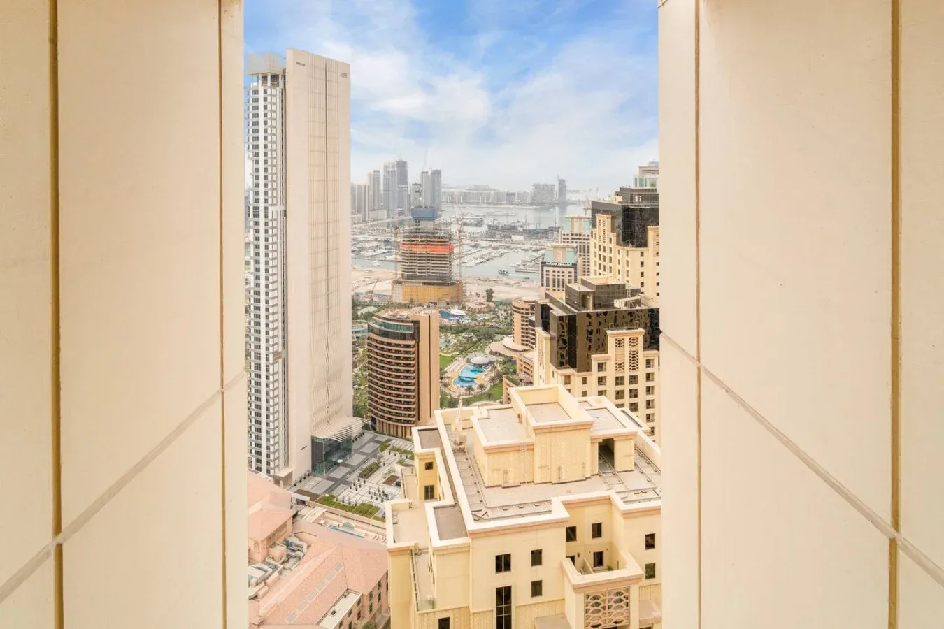 City skyline viewed through a window, with high-rise buildings beneath a blue sky.