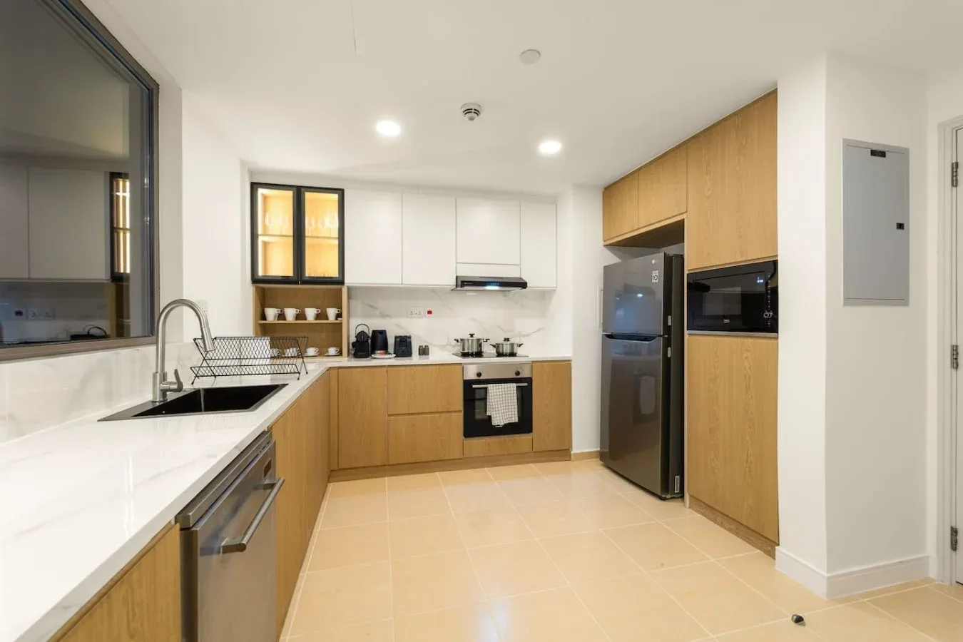 A modern kitchen with wood cabinetry, white counters, and stainless-steel appliances.